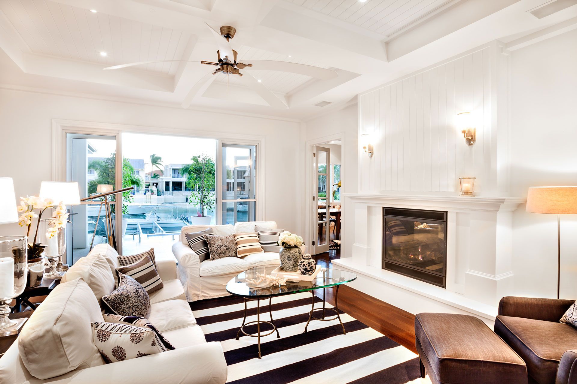 Living room with white walls, black and white striped rug, fireplace, and open doors to a pool.