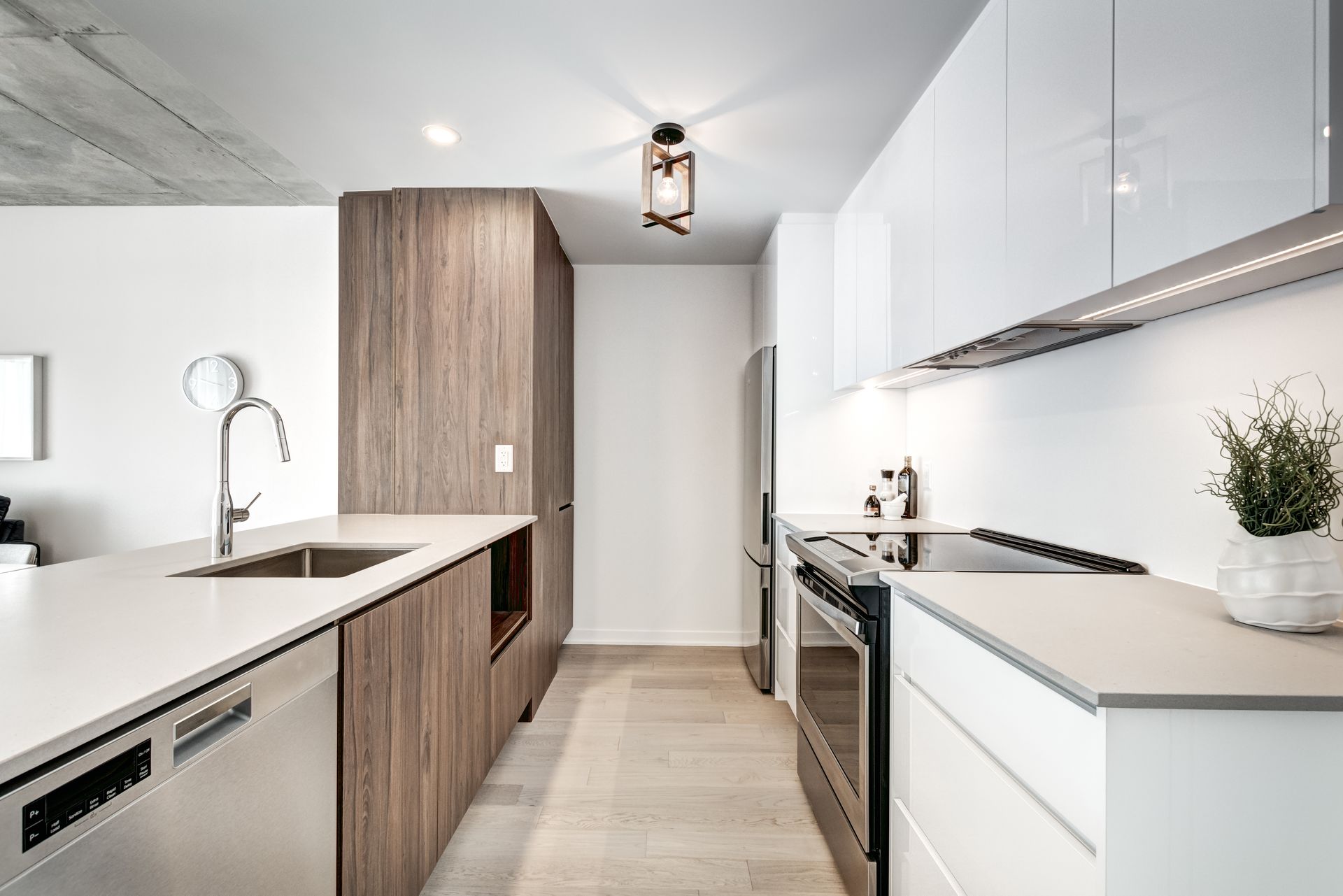 Modern kitchen with wood and white cabinets, stainless steel appliances, and a light grey countertop.
