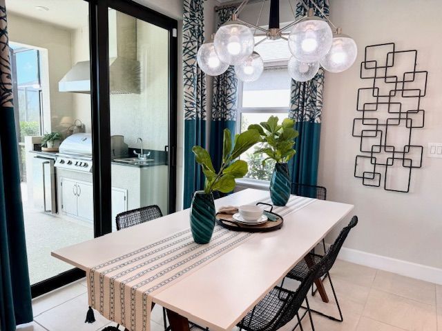 Dining area with white table, teal accents, and view of outdoor kitchen.