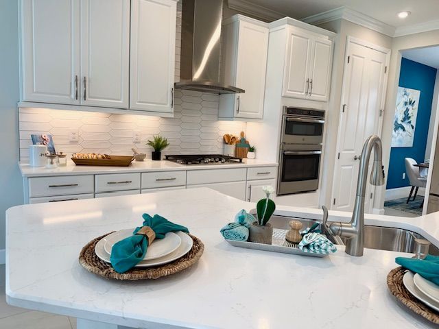 White kitchen with island, stainless steel appliances, and turquoise accents.