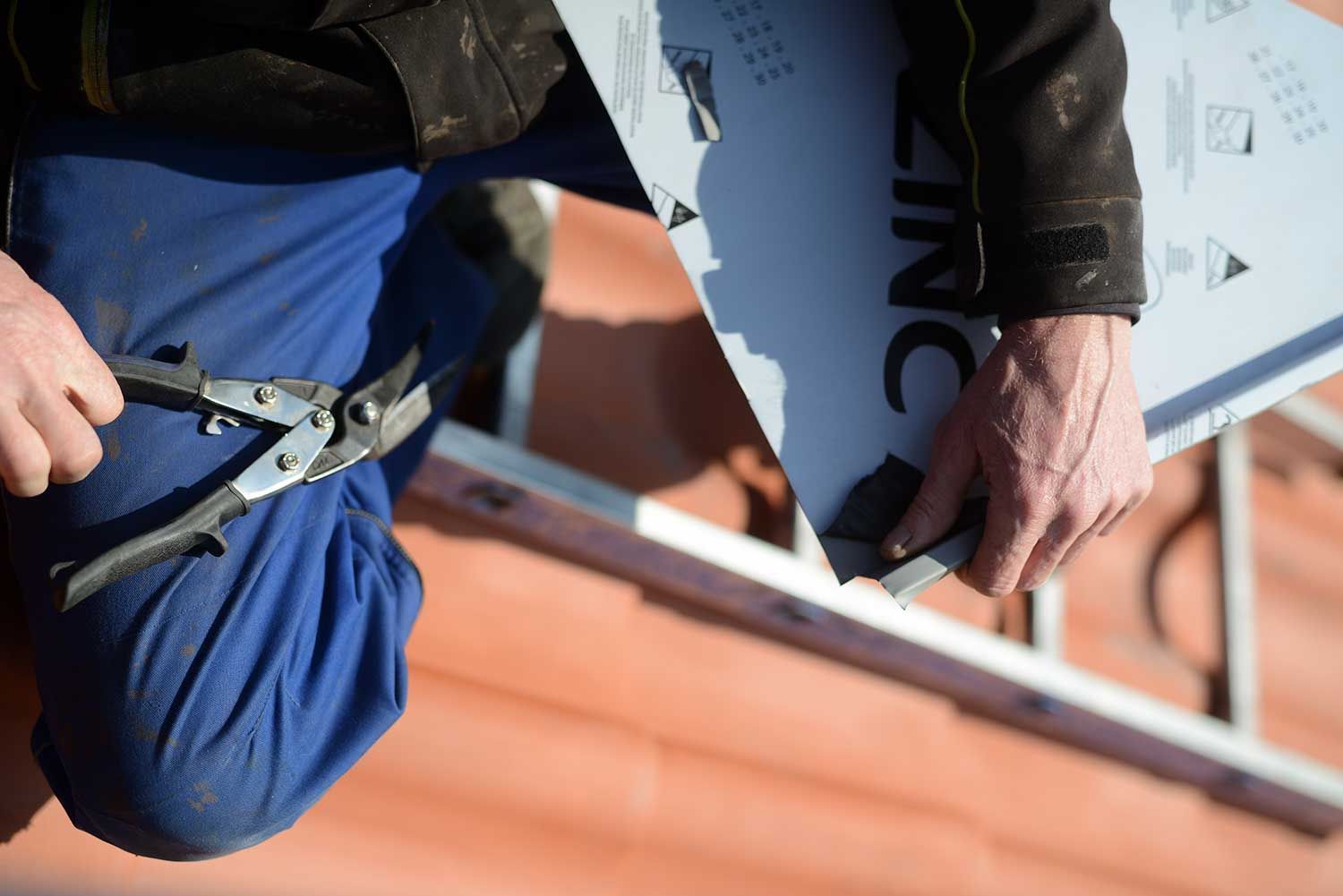 En mand klipper et stykke zink med en saks