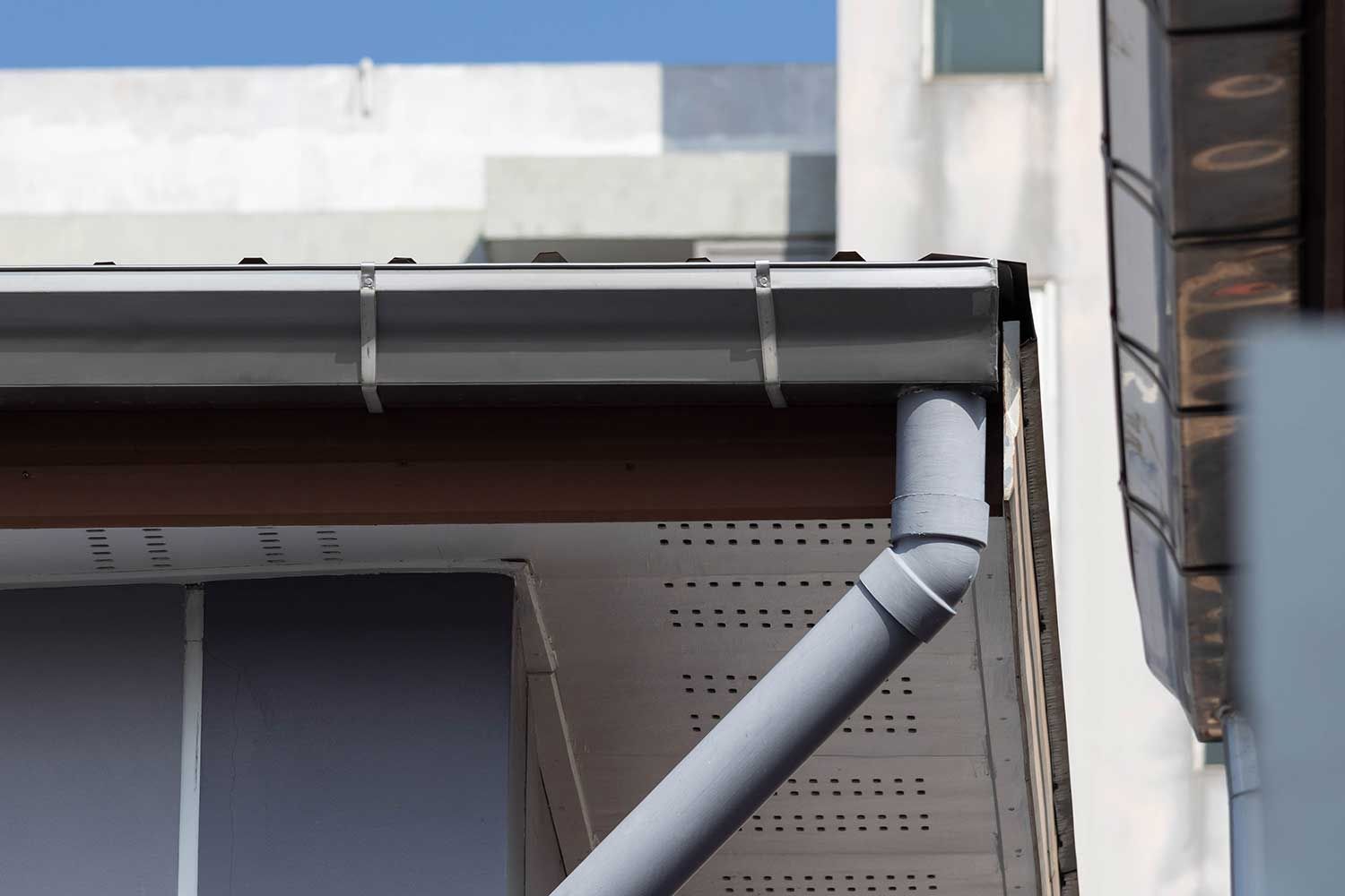 En tagrende på siden af en bygning med en blå himmel i baggrunden