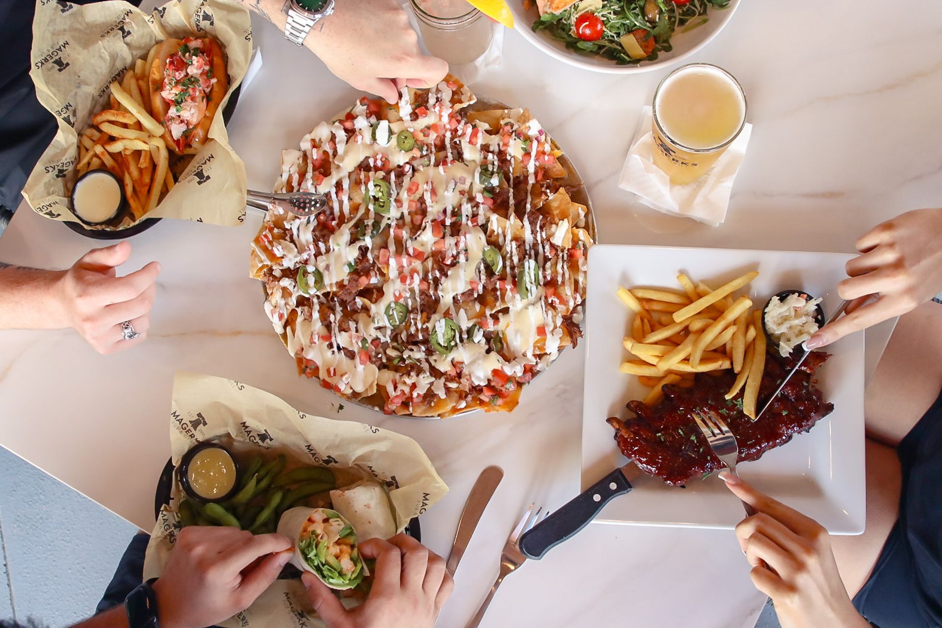 Six restaurant employees wearing matching shirts pose, some making peace signs.