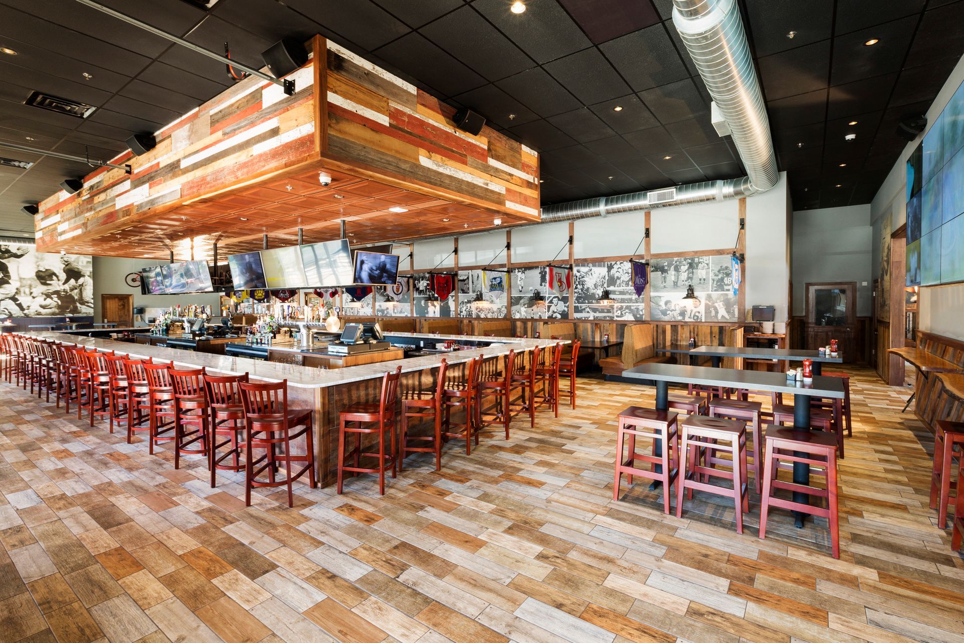 Interior of a crowded sports bar with tables, bar seating, TV screens, and servers carrying food.