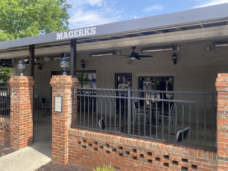 Magerks restaurant exterior, brick facade, metal railing, outdoor seating area, overcast day.