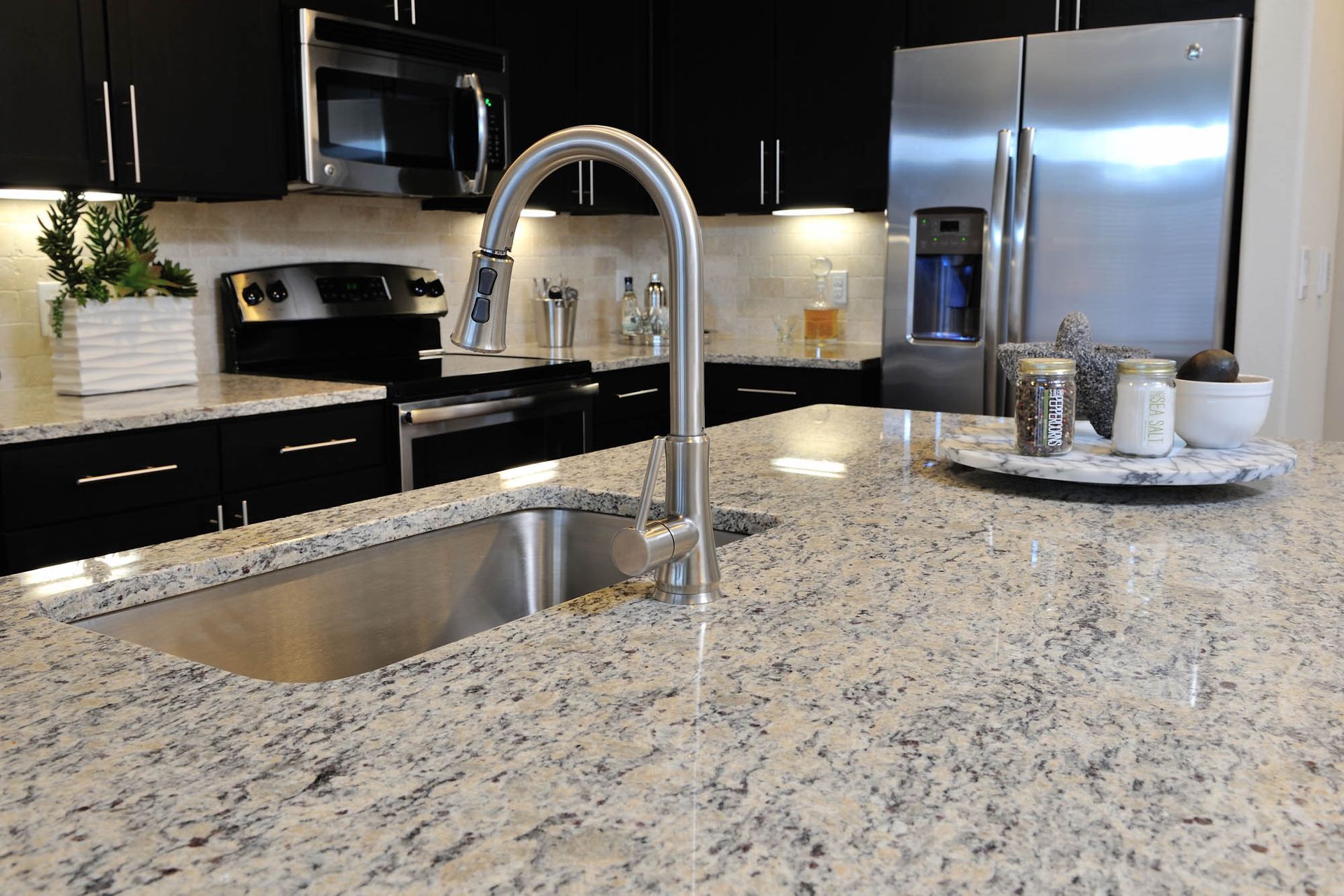 Modern kitchen island with a stainless steel sink and curved pull-down faucet.