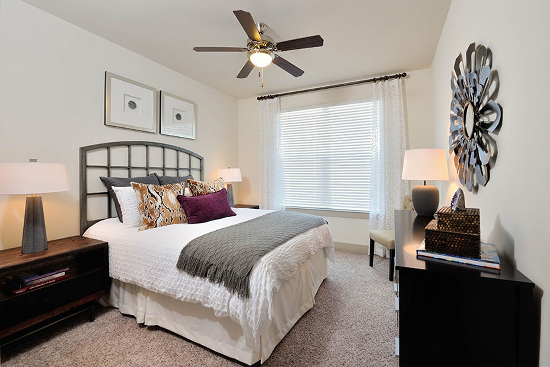 Bedroom with a queen bed, metal headboard, two nightstands, ceiling fan, and a window with blinds.