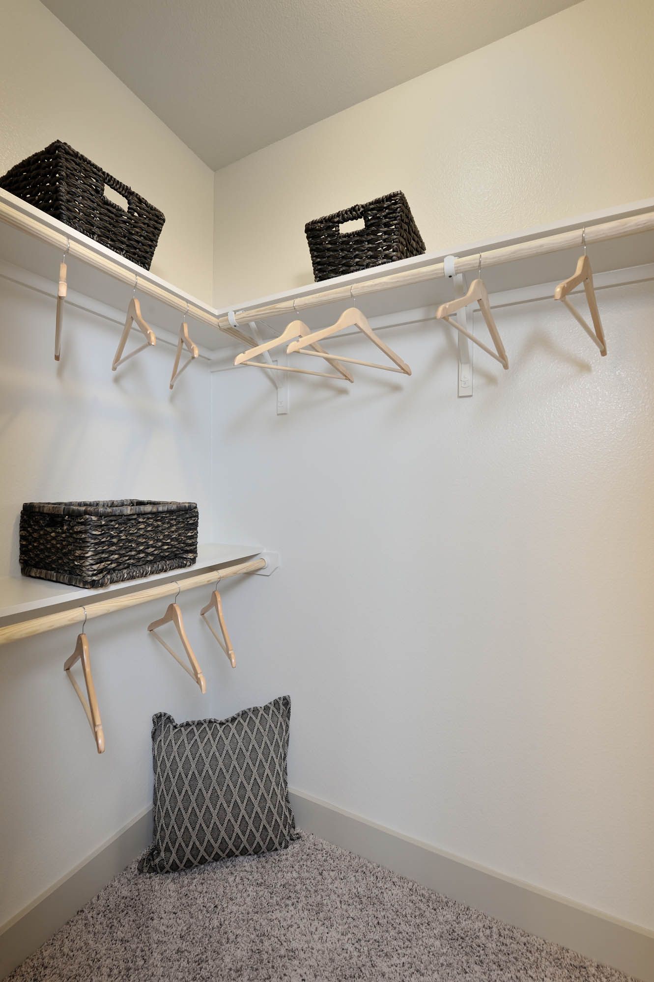 Walk-in closet with shelves, hanging rods, and woven baskets.