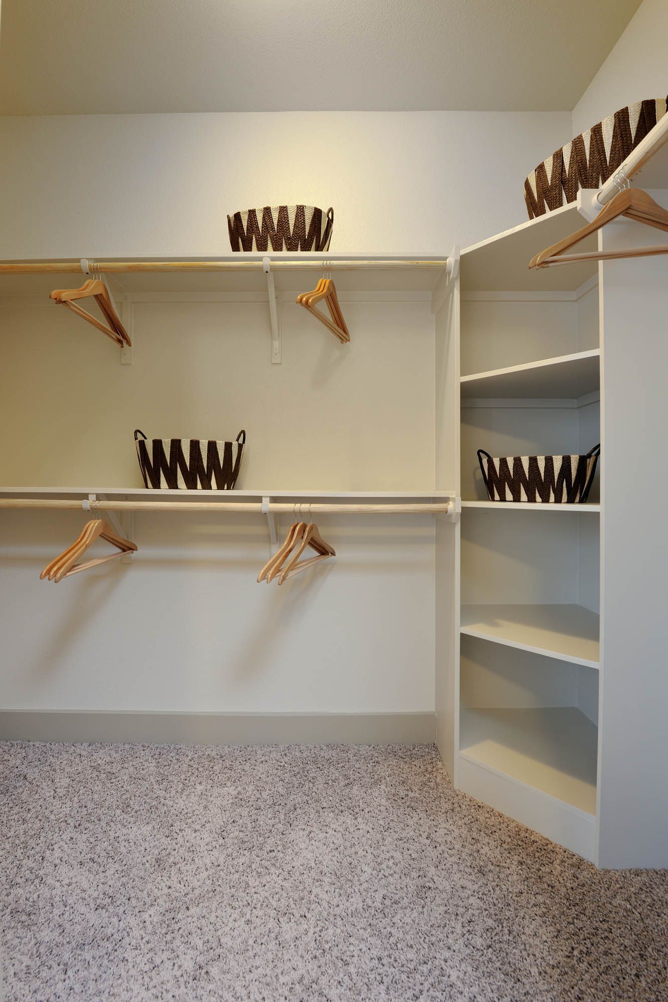Walk-in closet with hanging rods, shelves, and woven baskets.