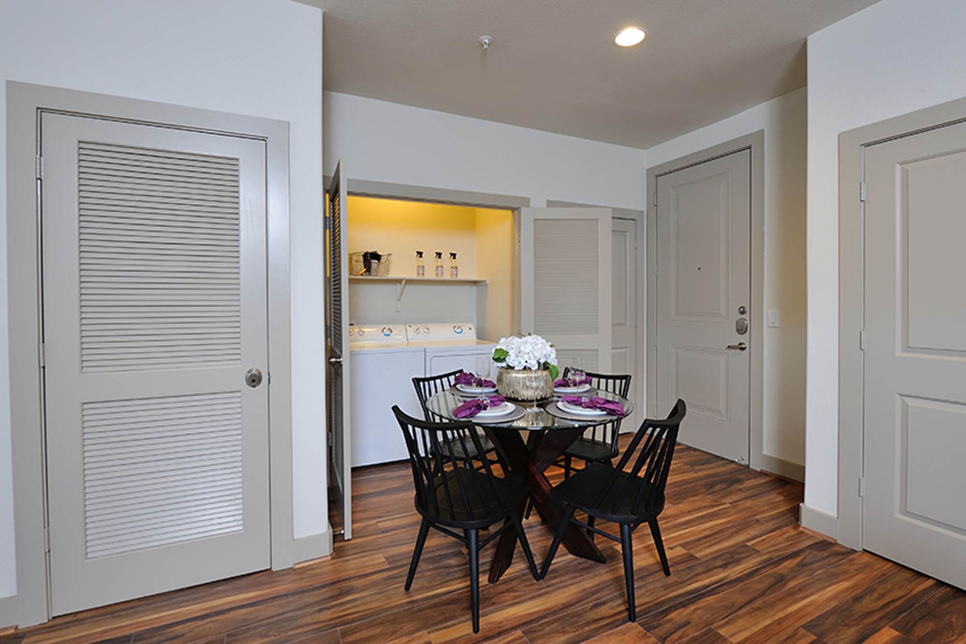 Interior of an apartment dining area with a laundry closet containing a washer and dryer.