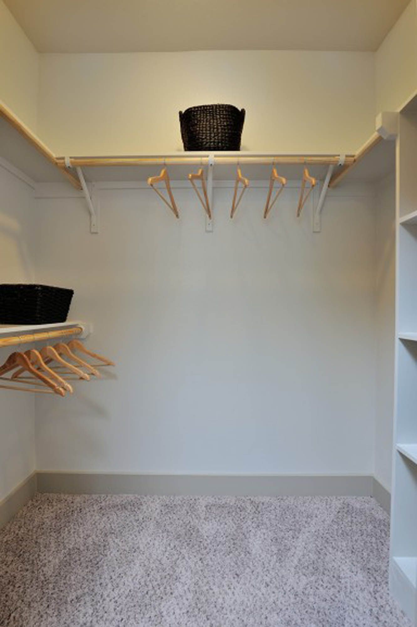 Walk-in closet with hanging rails, shelves, hangers, and a basket on top shelf.