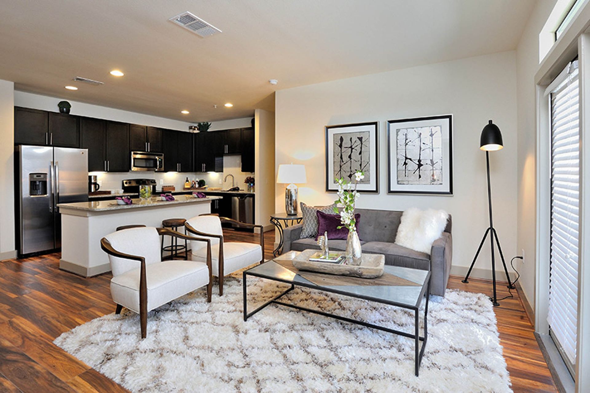 Open-concept living room and kitchen in a modern apartment with hardwood floors.