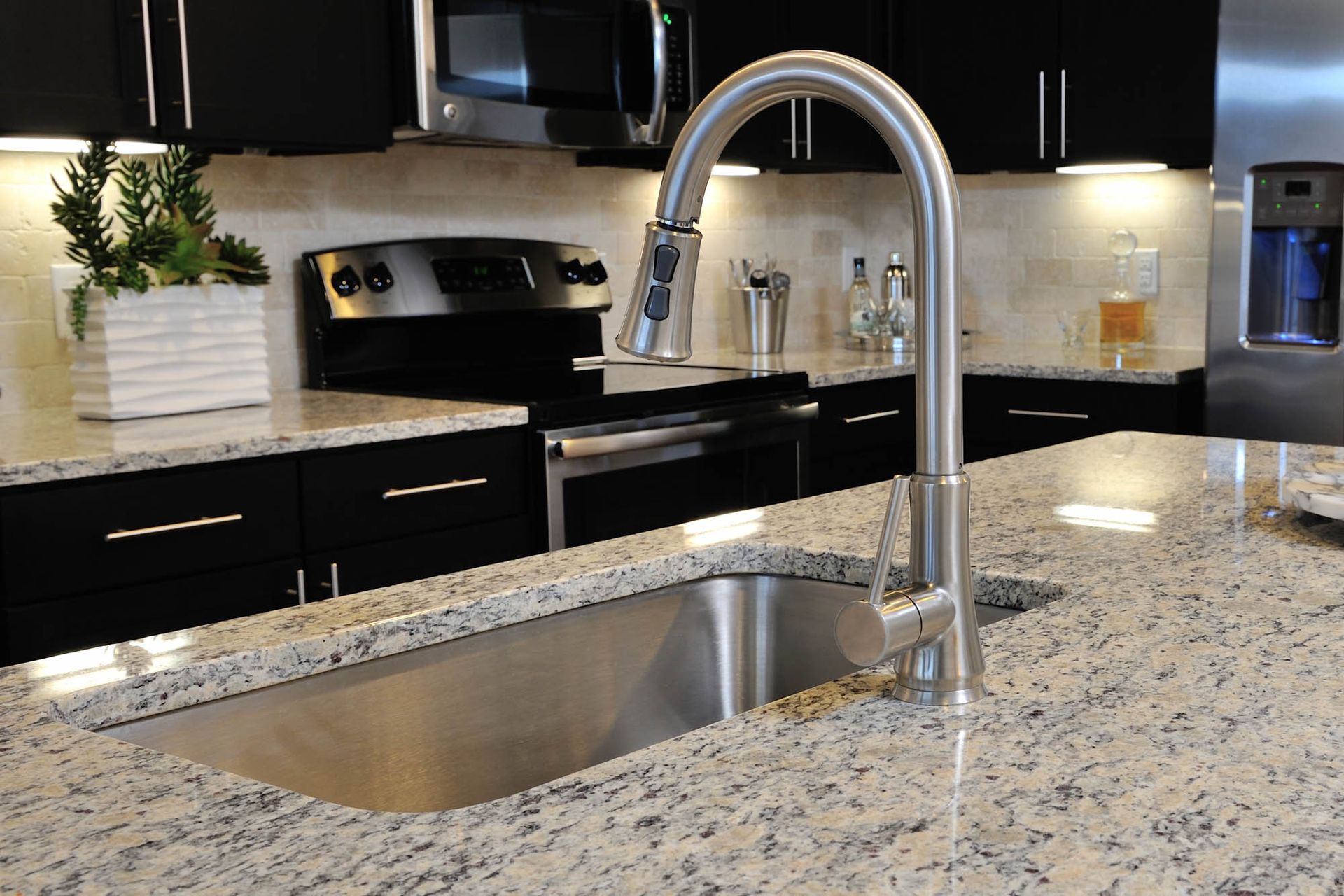 Modern apartment kitchen featuring a stainless steel sink faucet and granite countertop.