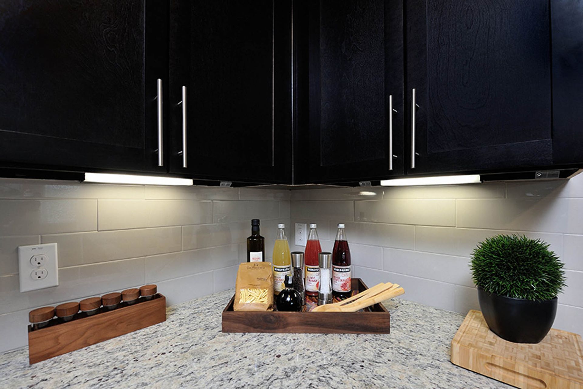 Kitchen with dark cabinets, under-cabinet lighting, and a spice tray on granite counter.