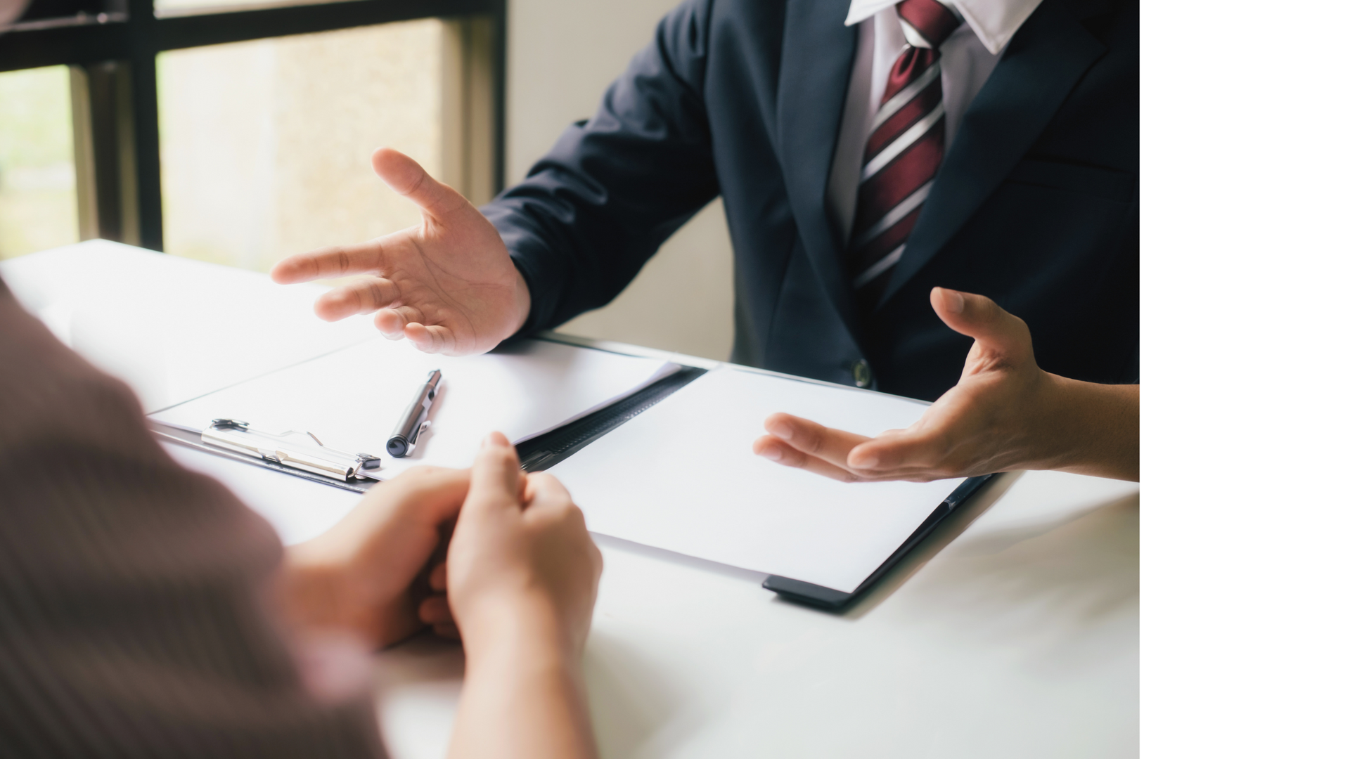 a man in a suit and tie is sitting at a table talking to a woman .