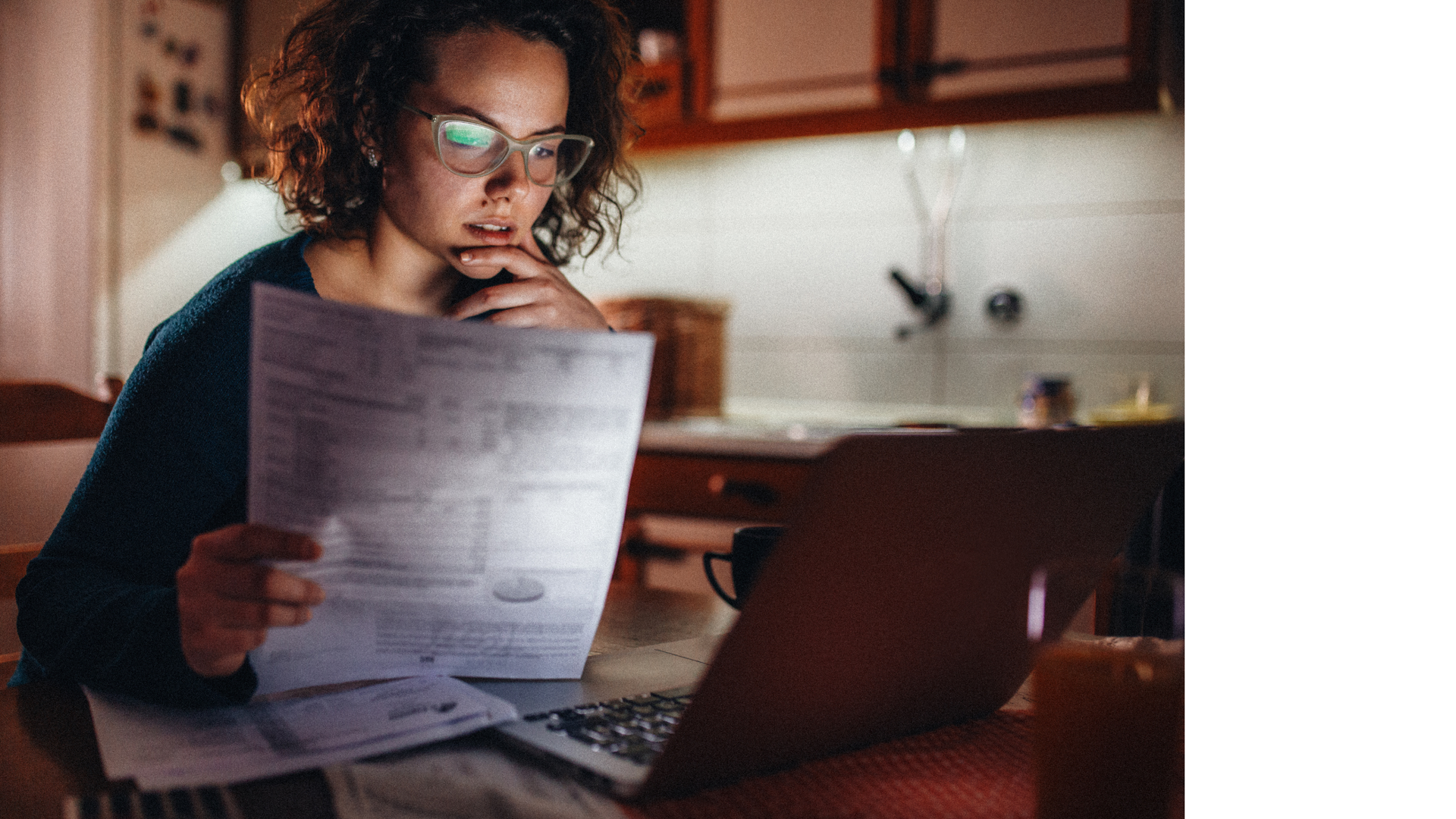 a woman is sitting at a table with a laptop and a piece of paper .