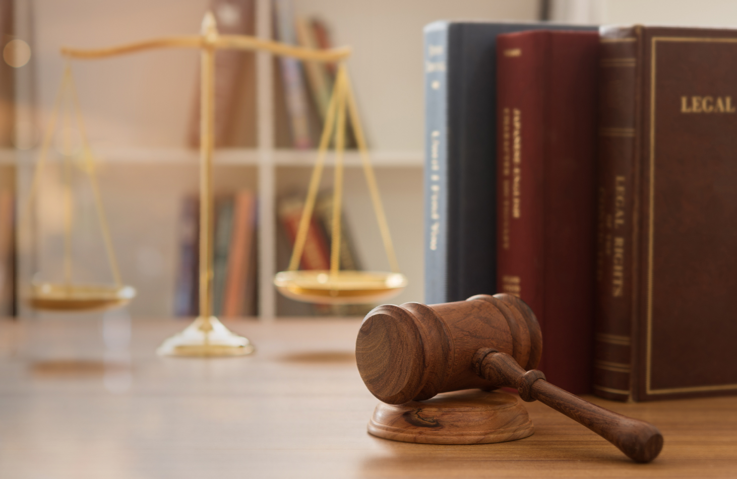 a wooden judge 's gavel is sitting on a wooden table next to a scale of justice .