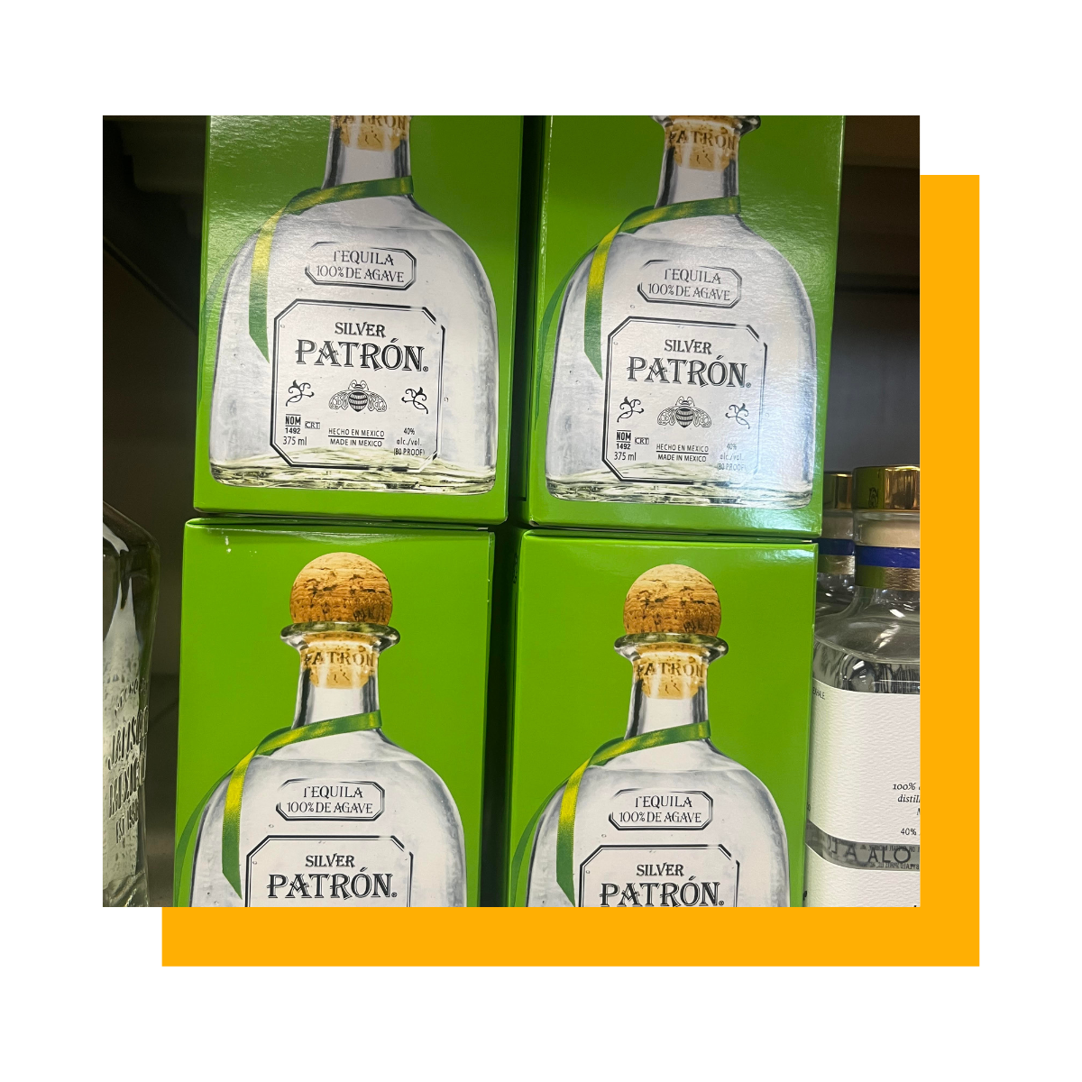 Four bottles of Patrón tequila in green boxes, on a shelf.