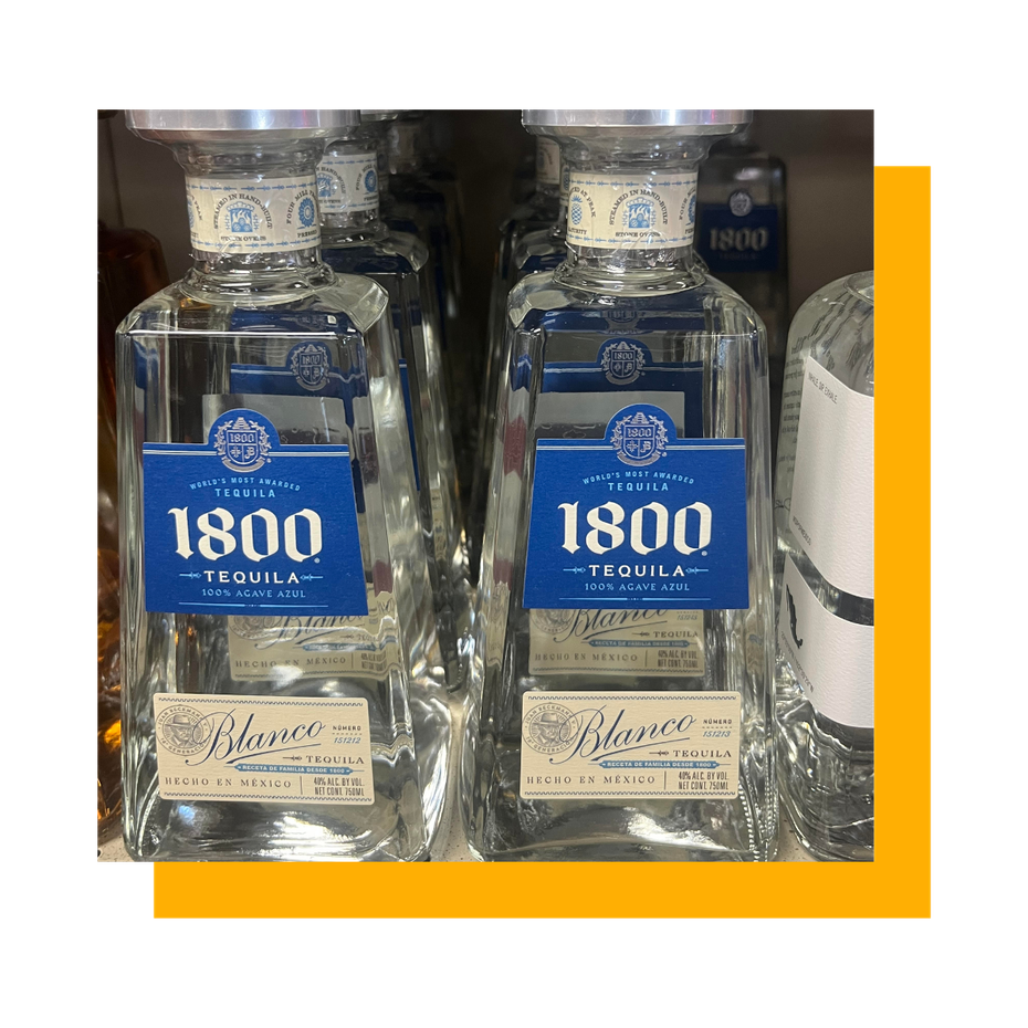 Two bottles of 1800 Blanco tequila on a shelf with blue labels and clear glass.