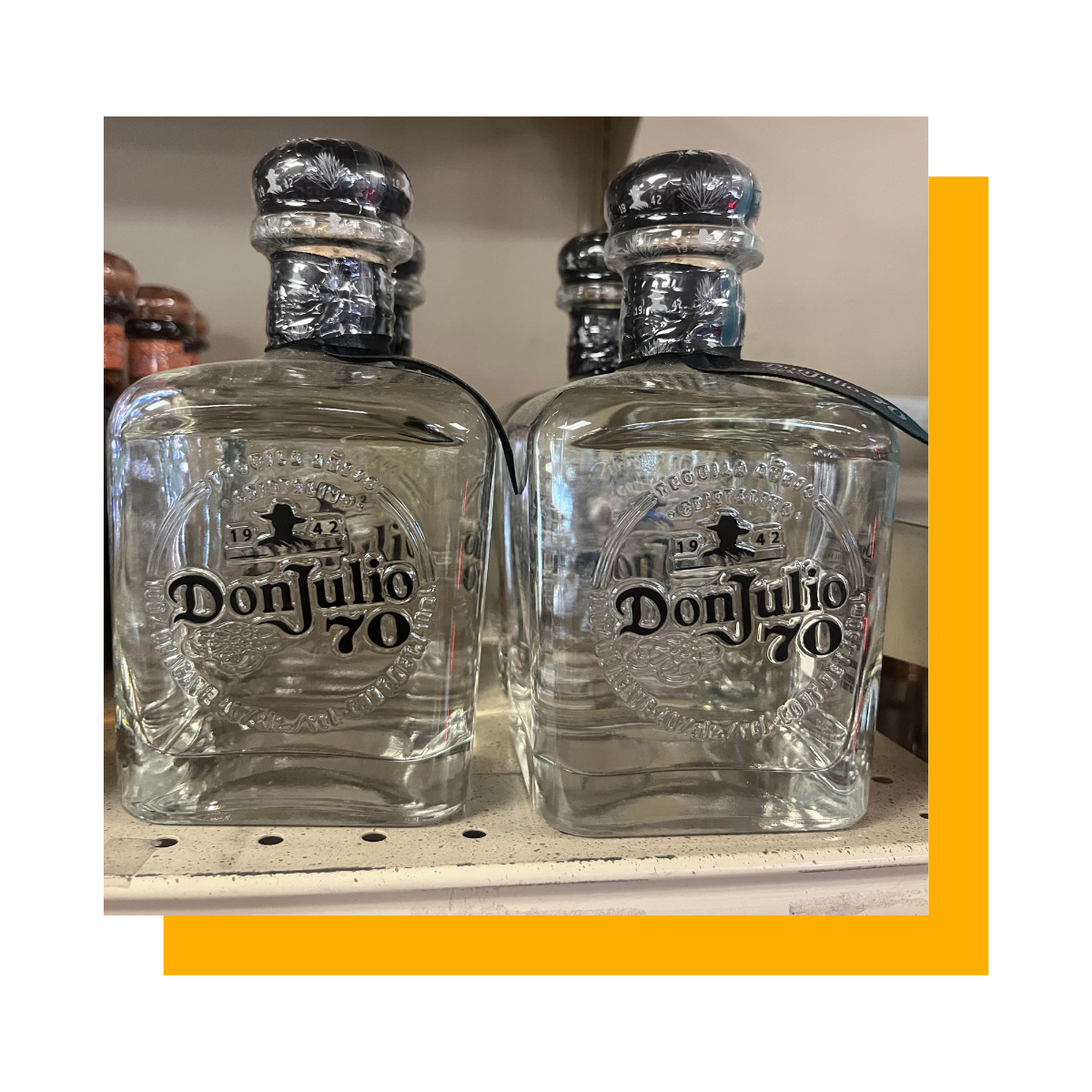 Two bottles of Don Julio 70 tequila on a shelf with other bottles in the background.