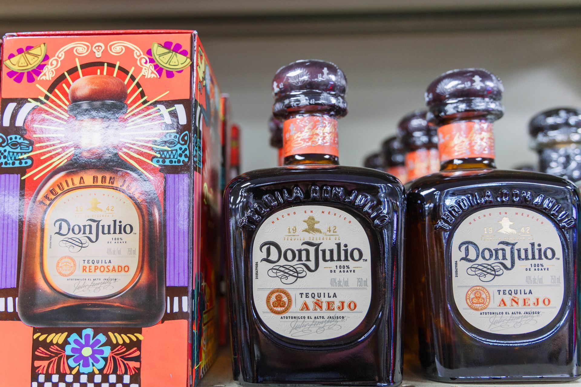 Don Julio Añejo tequila bottles on a shelf. The bottles are brown with a dark wooden stopper and label.