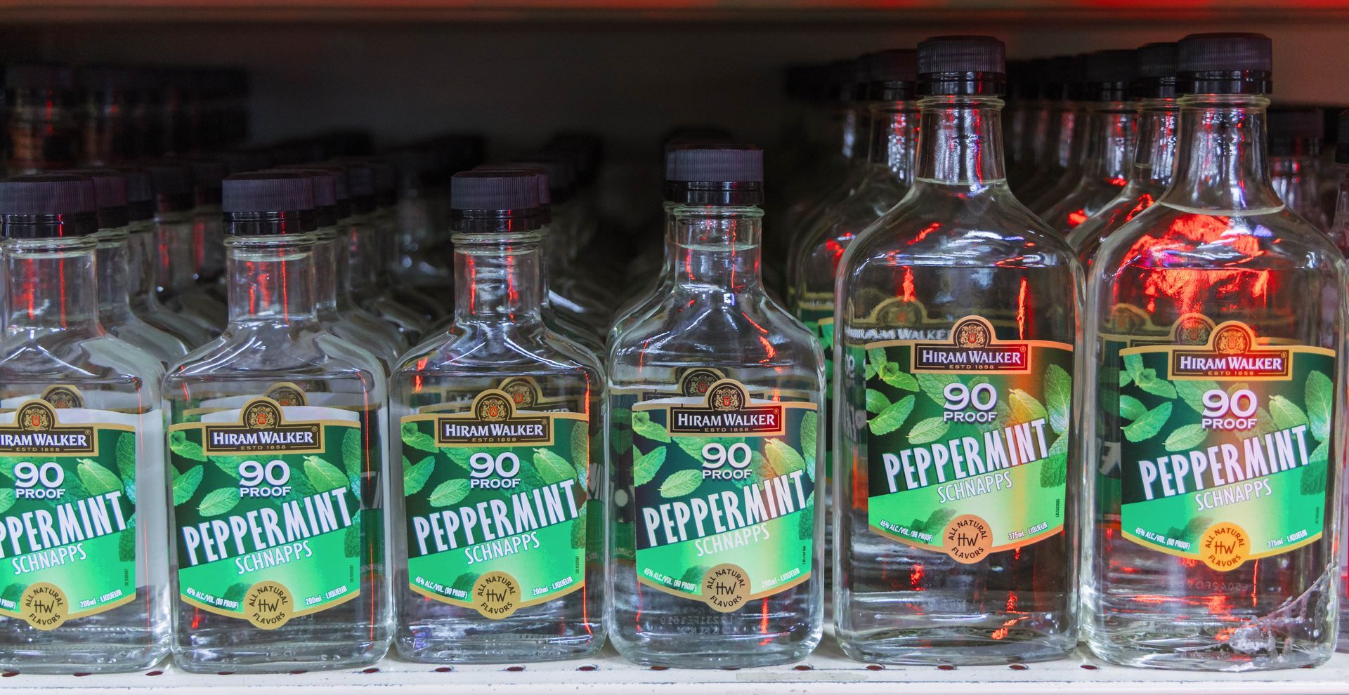 Bottles of De Kuyper Peppermint Schnapps, with green labels, on a shelf.