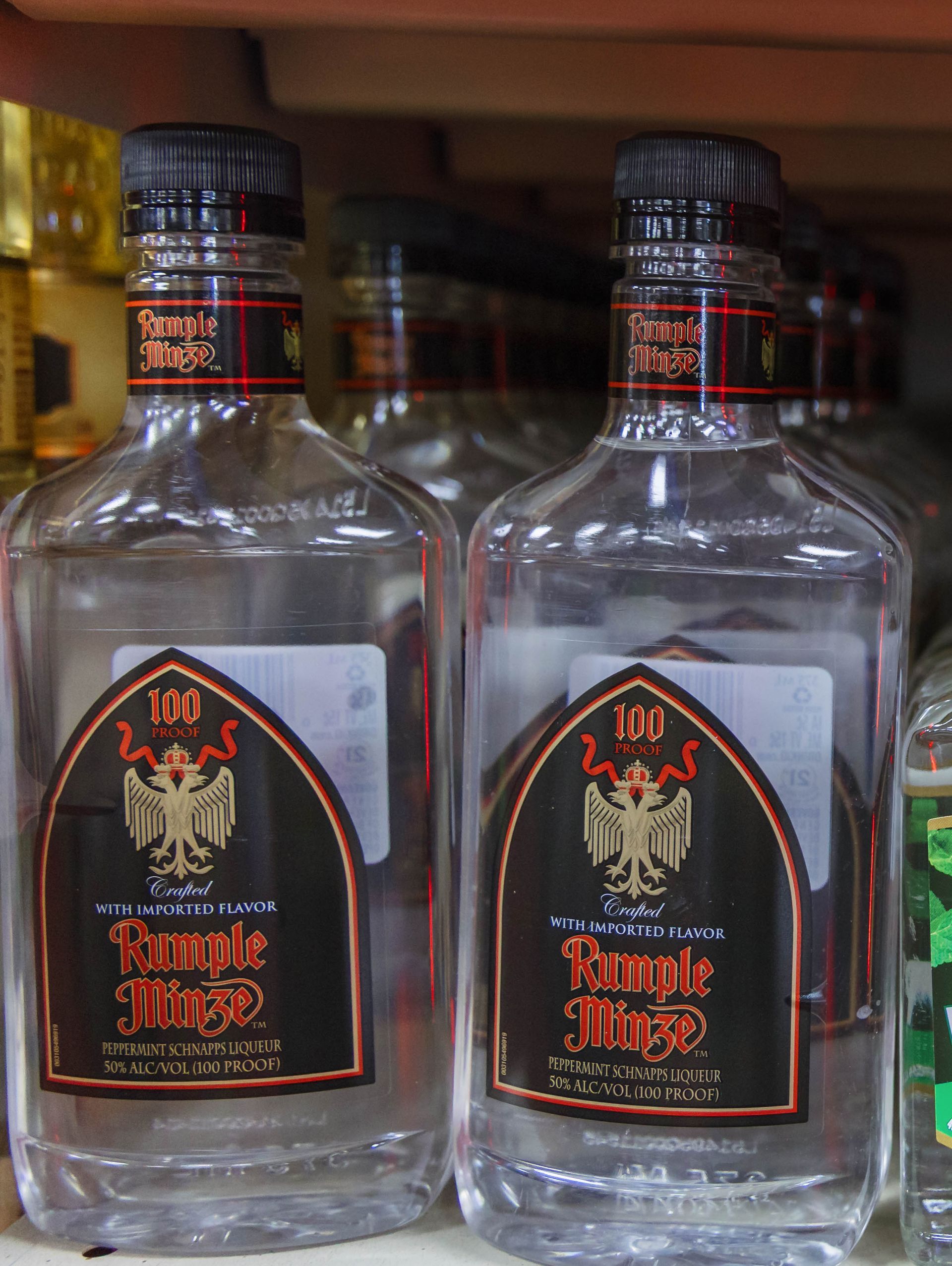 Two bottles of Rumple Minze liqueur with black and gold labels on a shelf.