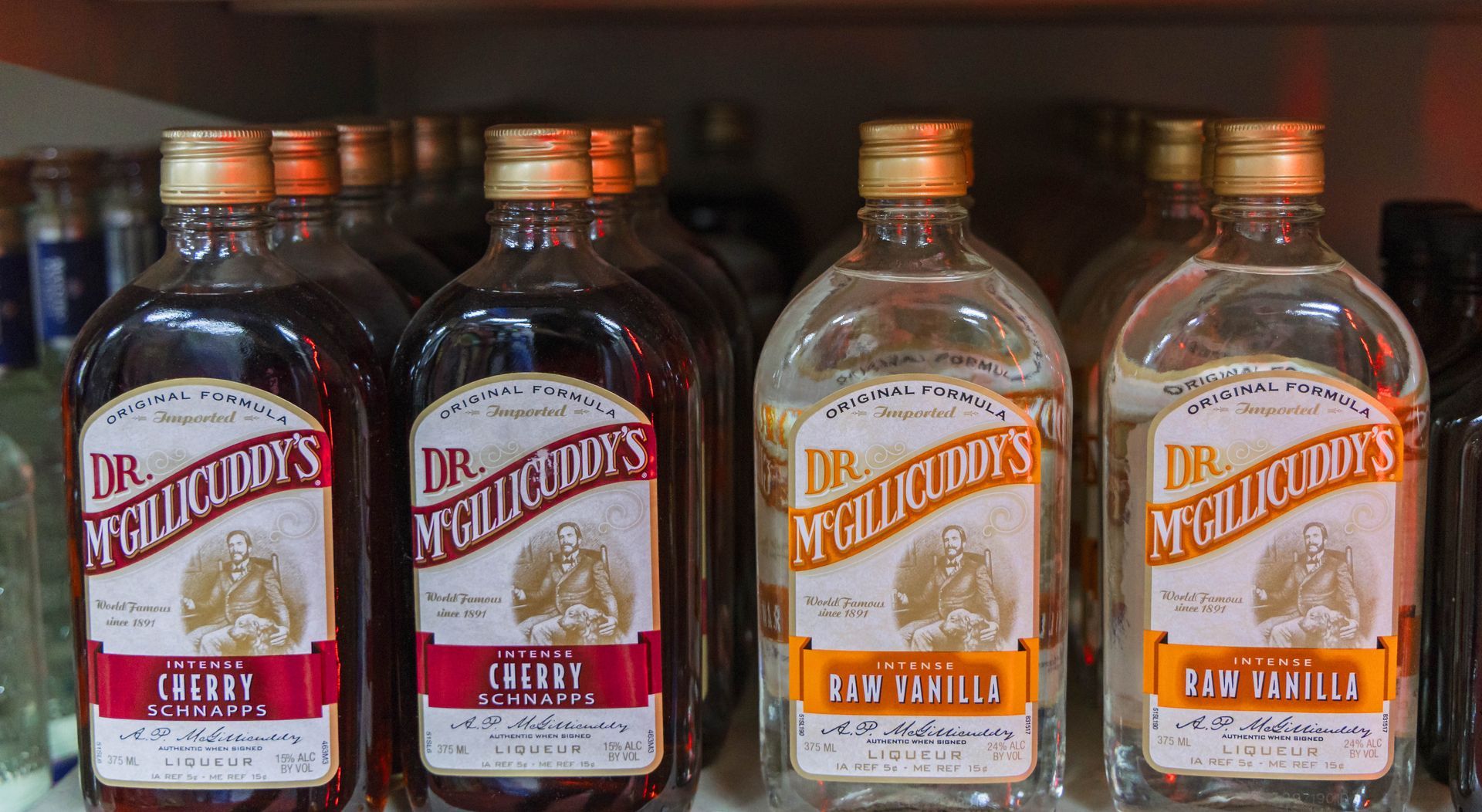 Bottles of Dr. McGillicuddy's liquors in cherry, gin vanilla, and rum vanilla, on a shelf.