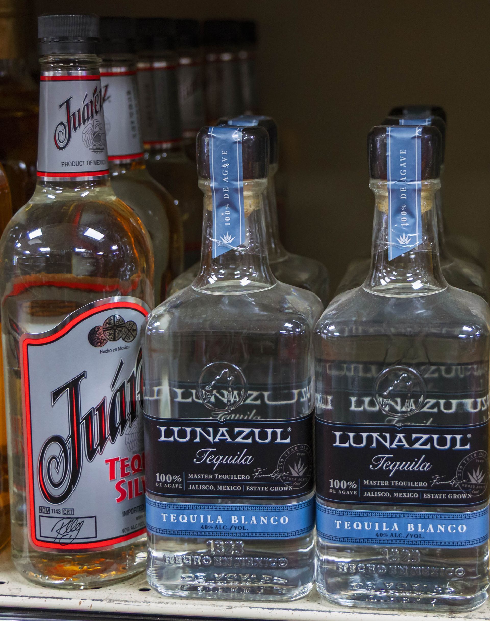 Bottles of tequila on a shelf. Two bottles of Lunazul Tequila, blue and black labels,