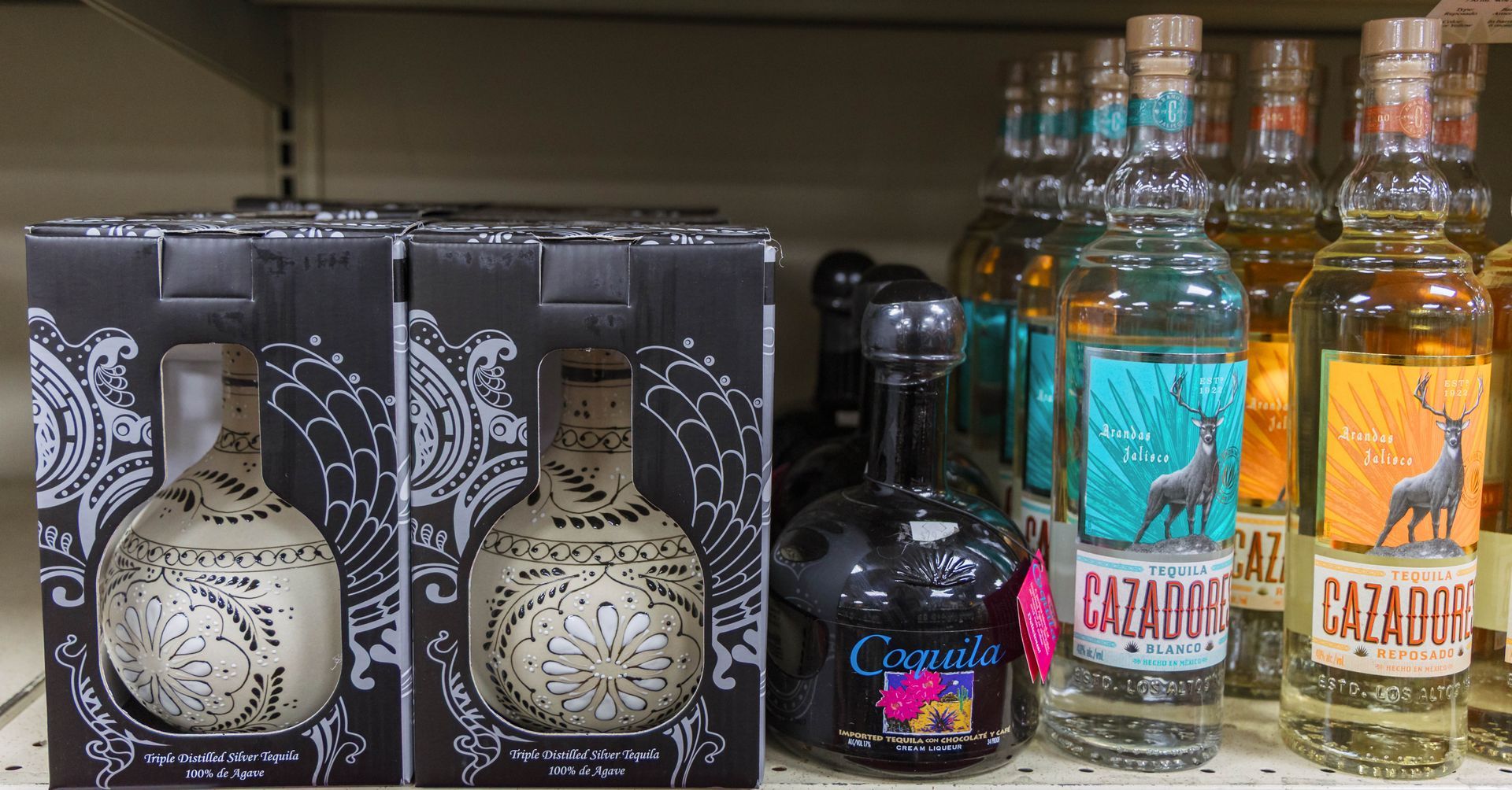 Bottles of tequila on a shelf; some in boxes, some with labels.
