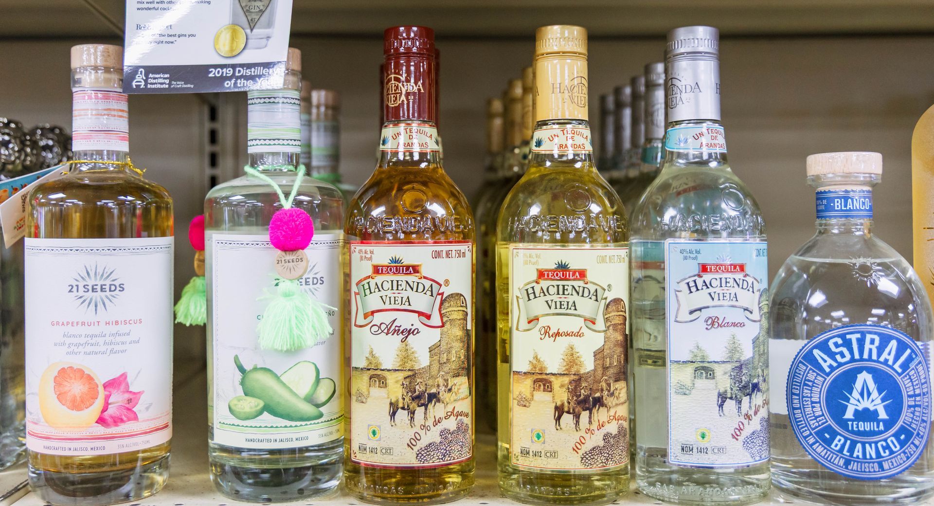 Bottles of liquor on a store shelf; various labels and colors.