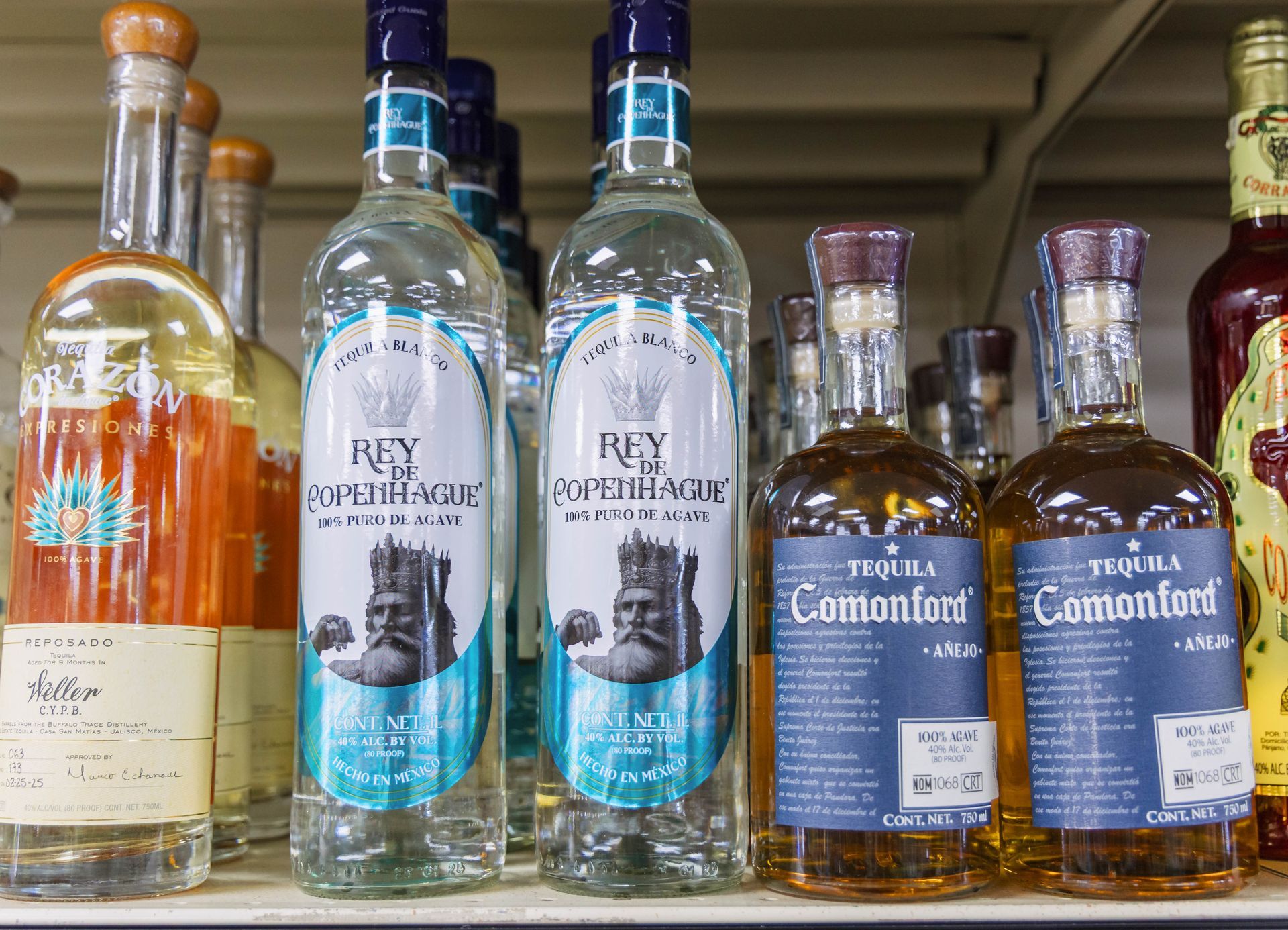 Bottles of tequila on a shelf, including Rey Comonfort and Tequila Comonfort brands.