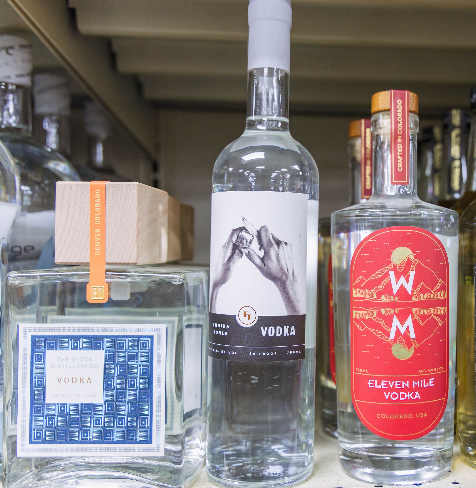 Bottles of vodka on a shelf, including one with two hands on the label.