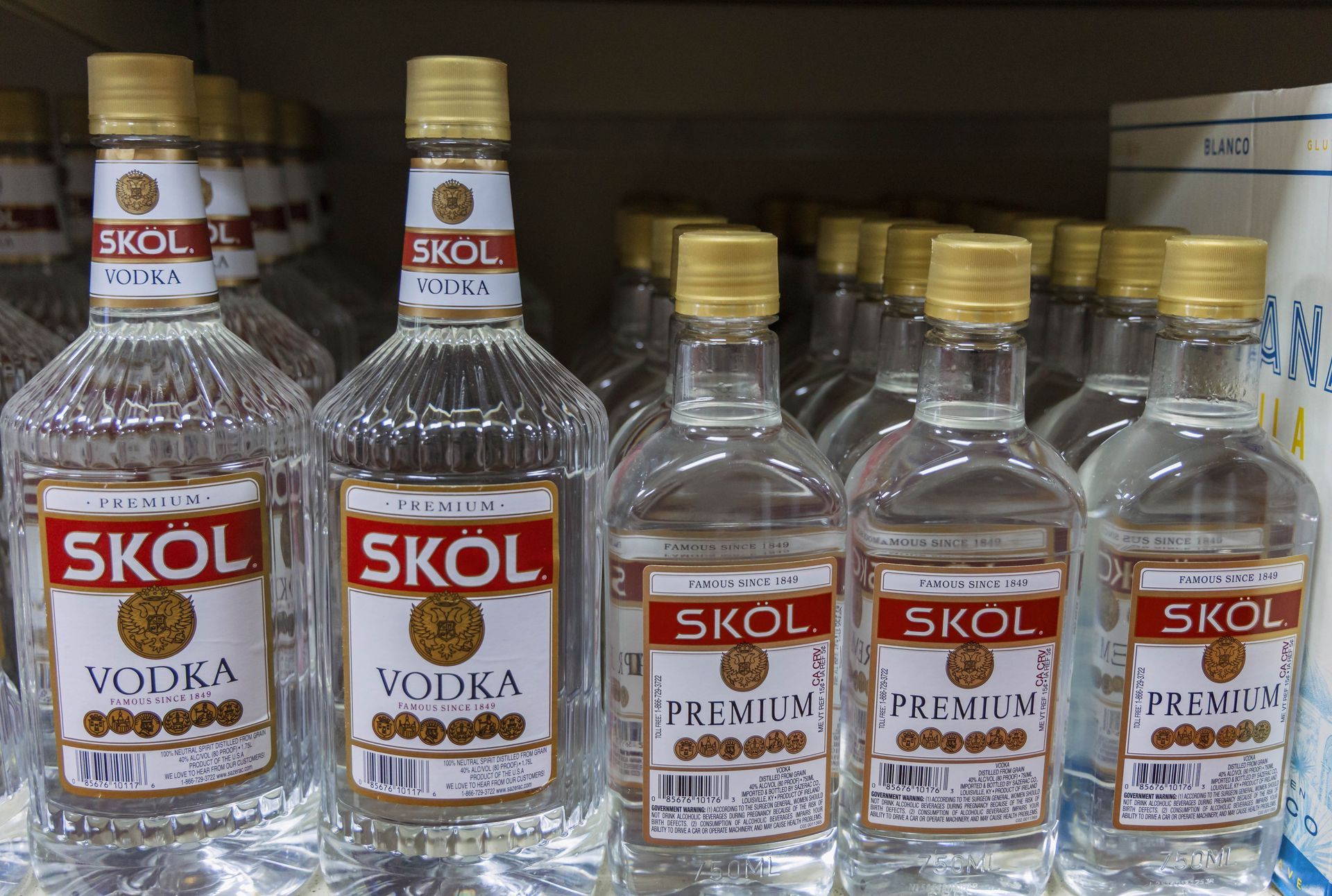 Bottles of Skol Vodka on a store shelf, featuring clear bottles with red and gold labels.