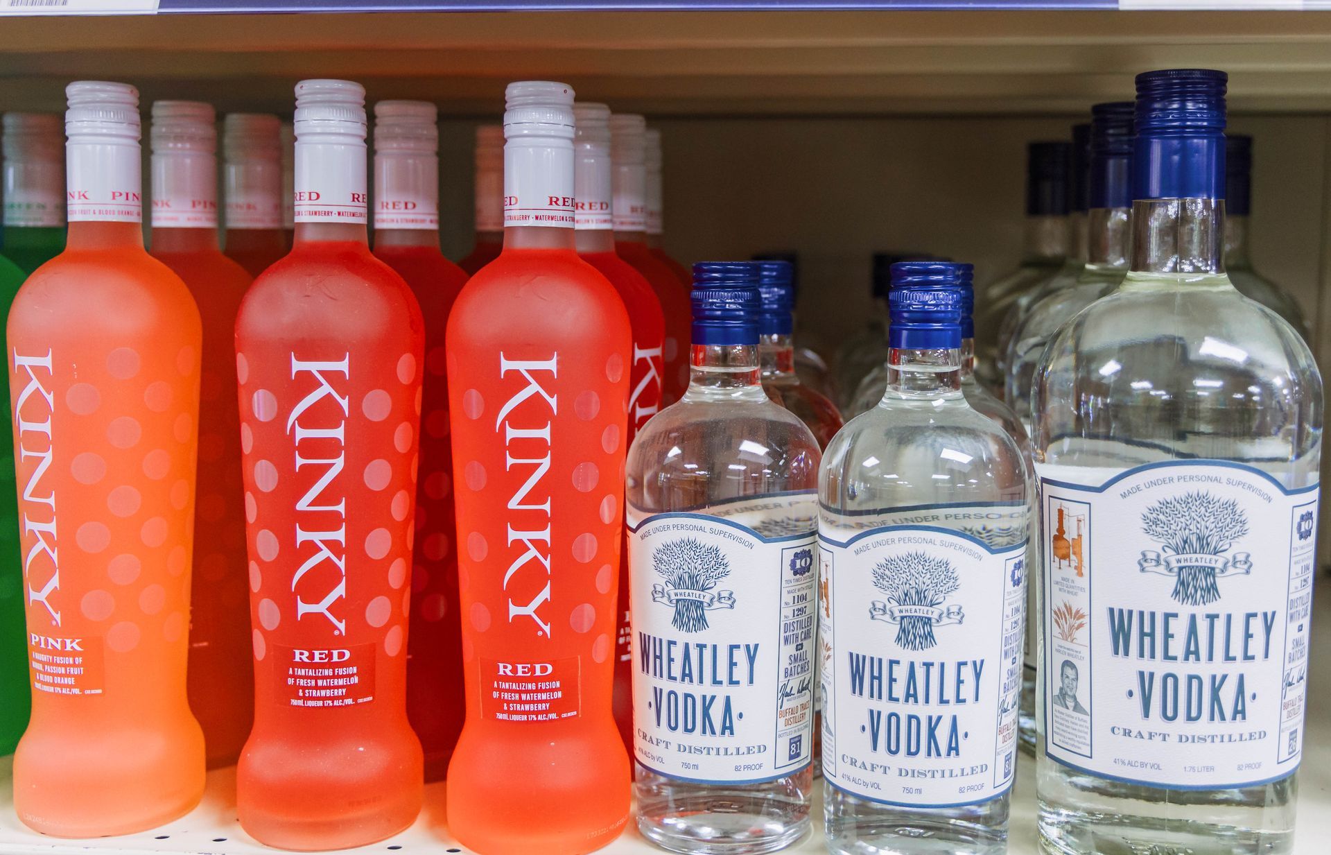 Bottles of Kinky pink vodka and Wheatley clear vodka on a shelf.