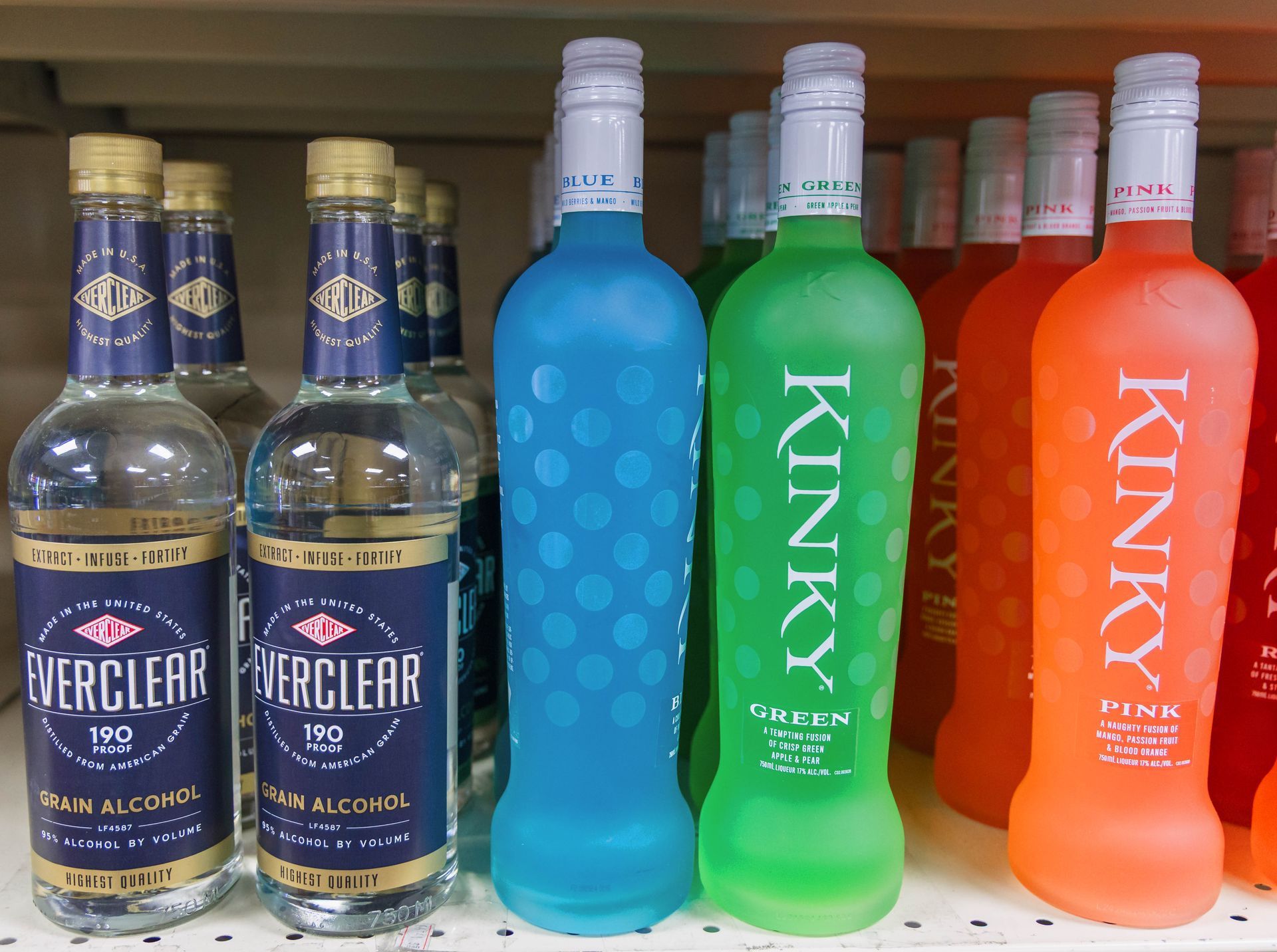 Bottles of liquor on a shelf: Everclear and Kinky in blue, green, and pink, with white caps.