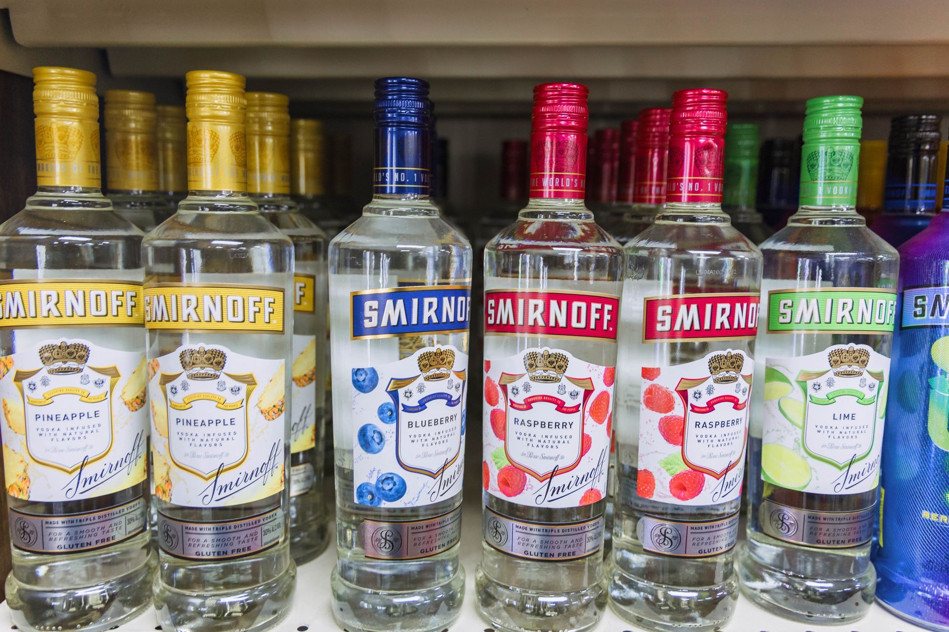 Shelves of Smirnoff vodka bottles in various flavors, with colorful labels and caps.