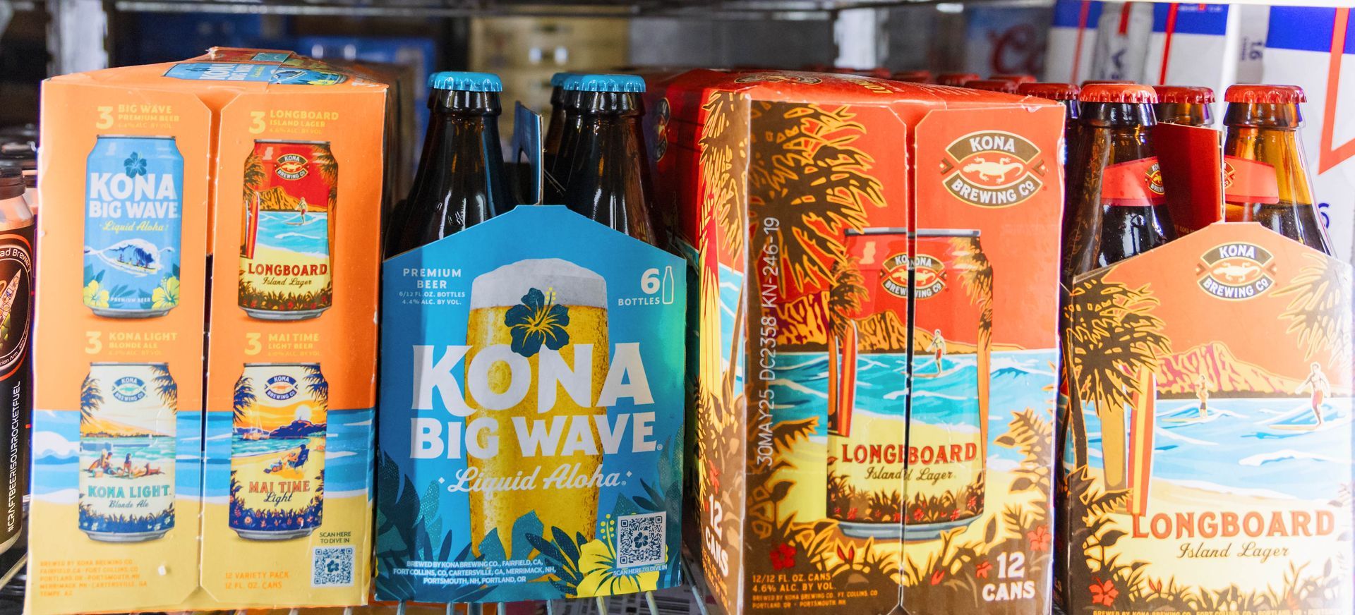 Kona beer bottles and cans in a refrigerator, with tropical themed packaging.