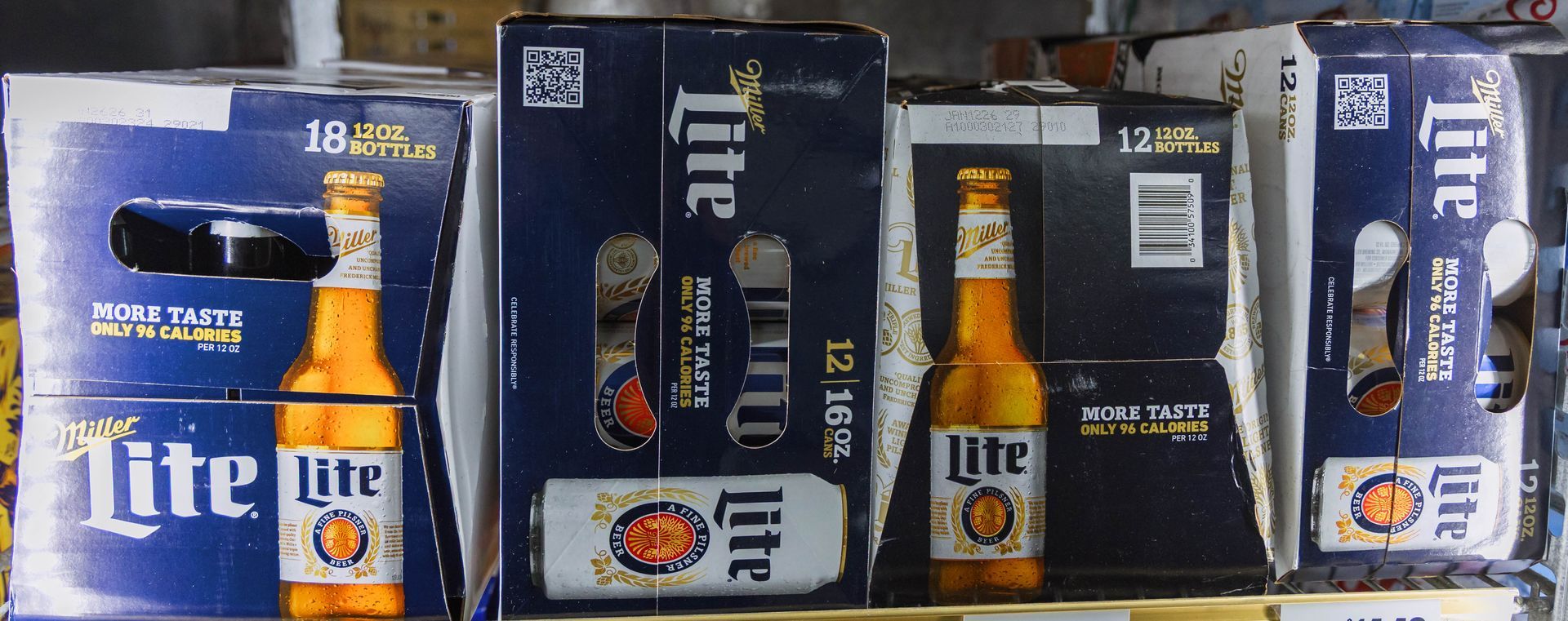 Cardboard boxes of Miller Lite beer on a shelf.