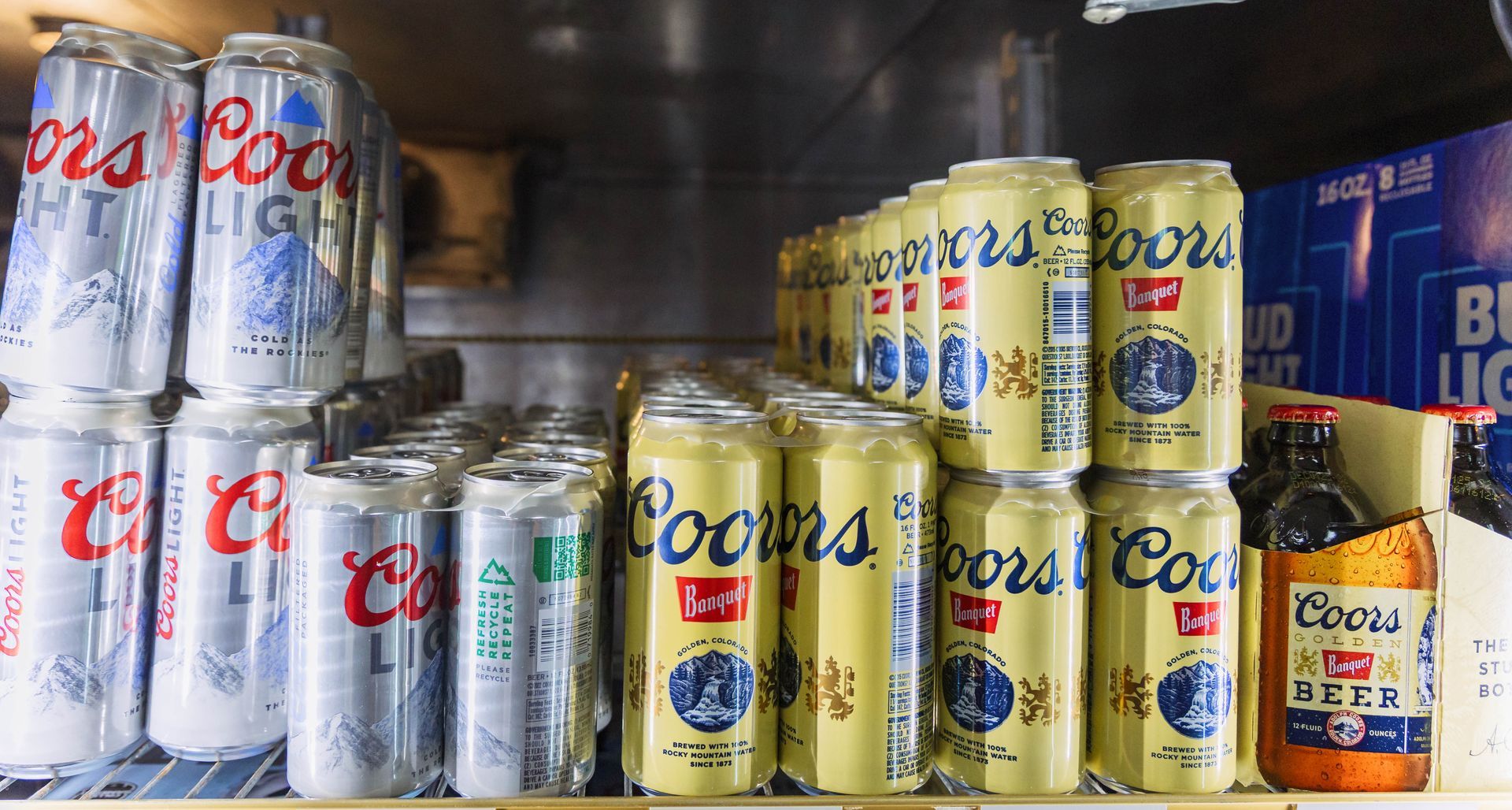 Shelved assortment of Coors Light and Coors beer cans, along with a single bottle.