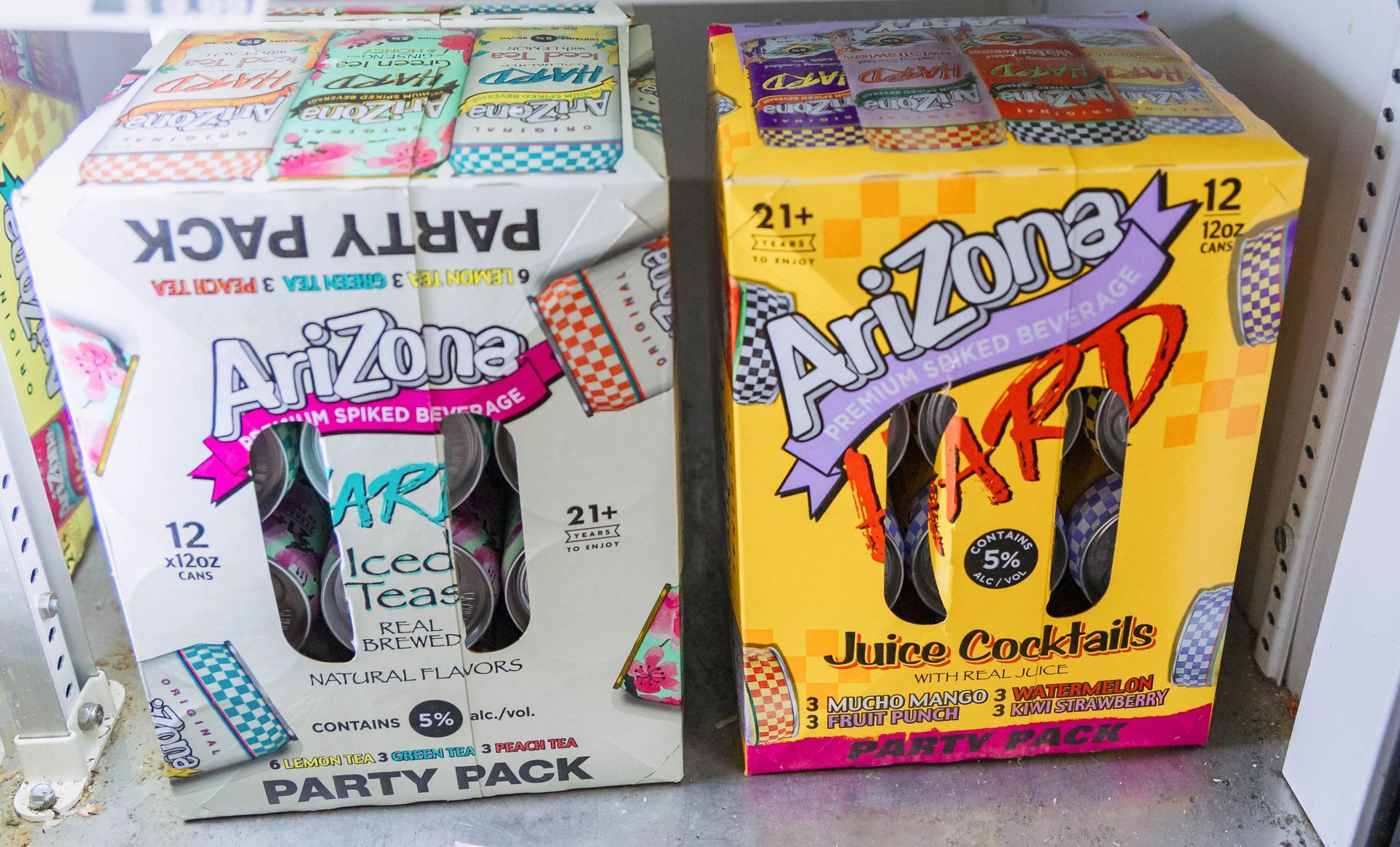 Two Arizona Tea party packs: one white, one yellow, with black ice tea cans.