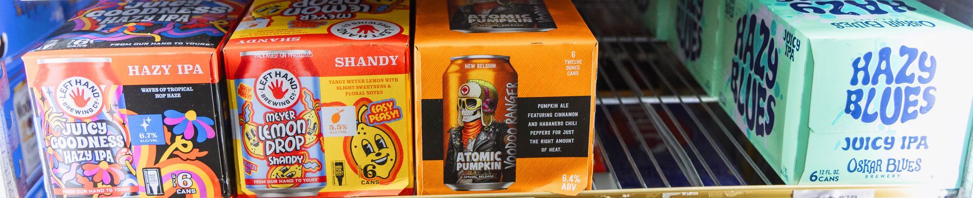 Boxes of canned beverages in a refrigerated display. Colors are orange, pink, and blue.