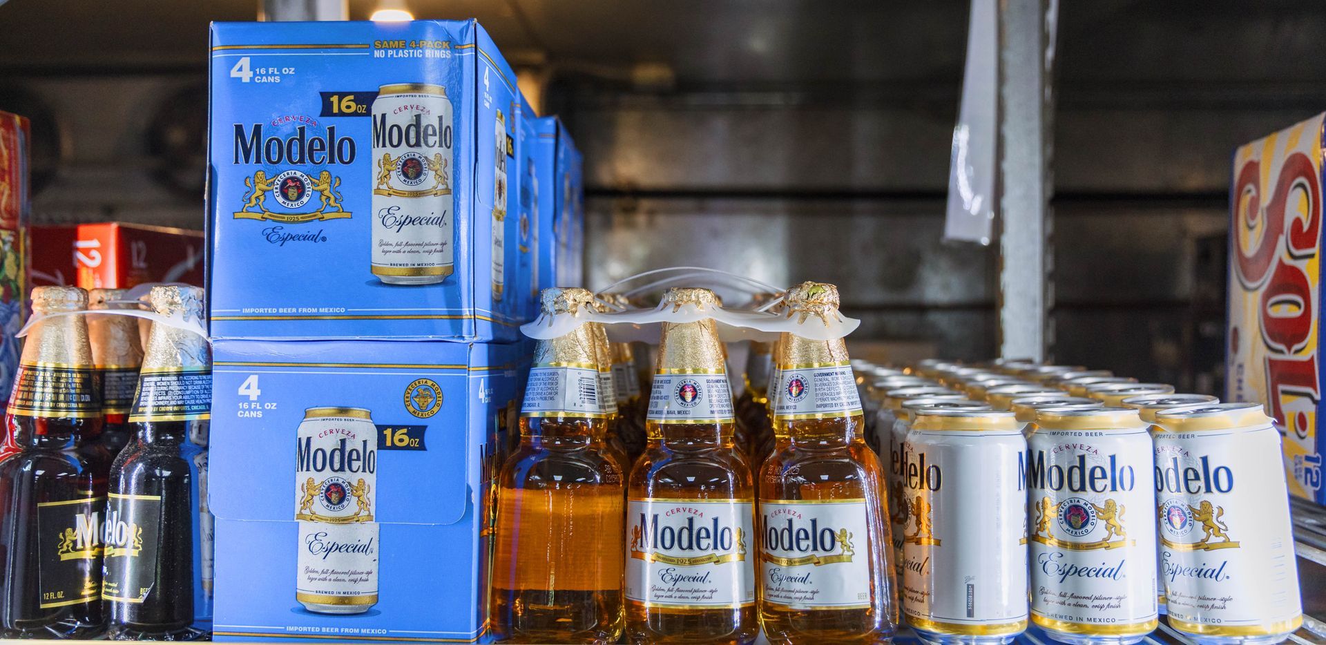 Shelves stocked with Modelo beer bottles and cans, a variety of packaging.
