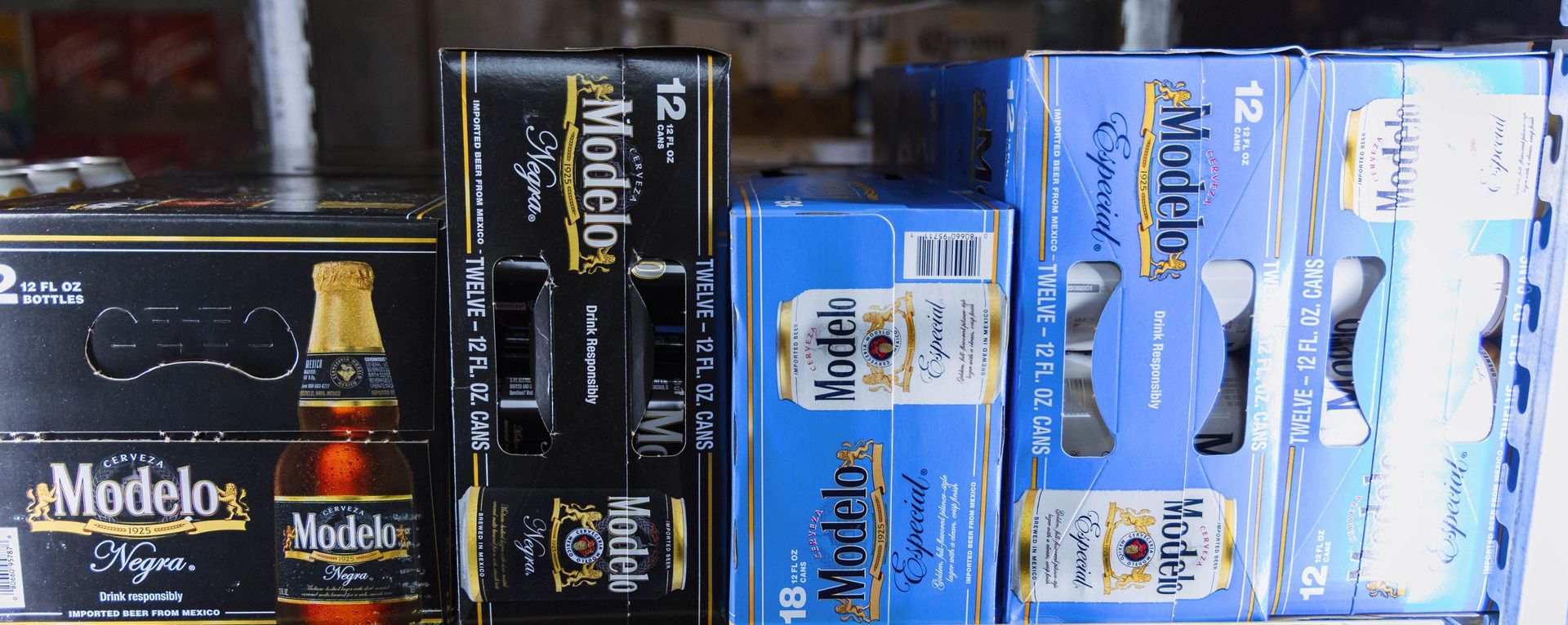Shelves stocked with Modelo beer cases and bottles in a store.