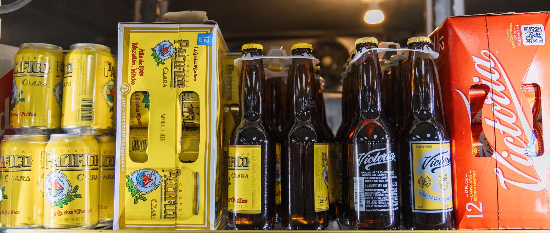Assortment of beer cans and bottles in yellow and brown packaging.