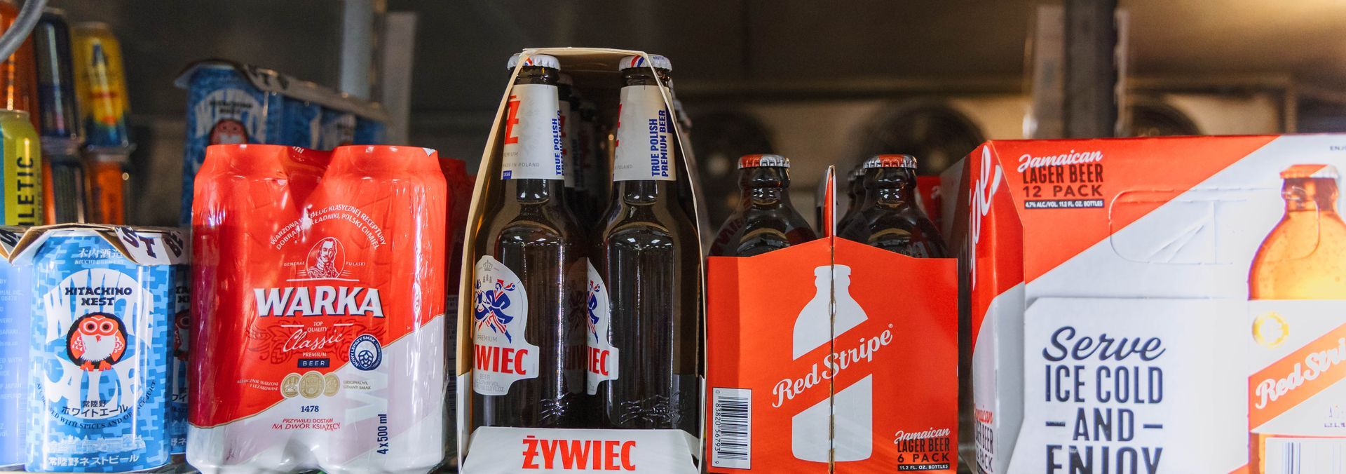 Shelves filled with various brands of beer, including Warka, Żywiec, and Tyskie.