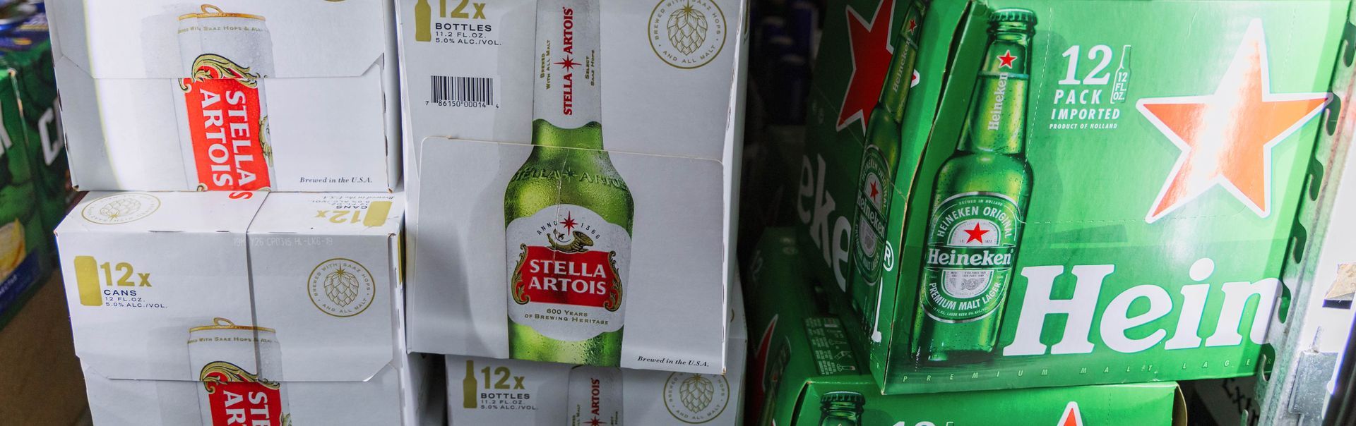 Cases of beer, including Stella Artois and Heineken, stacked in a store.