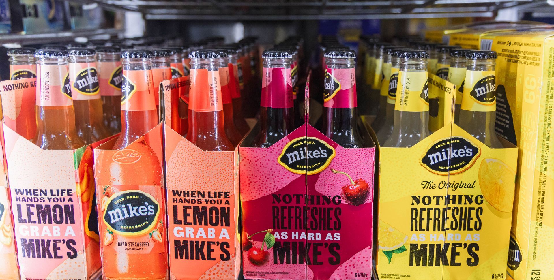 Bottles of Mike's Hard Lemonade and other flavors in a retail store, various colors and packaging.