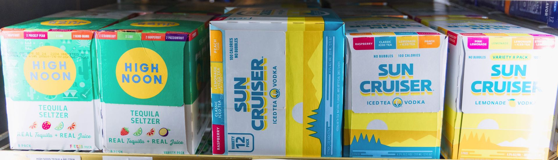 Cans of High Noon and Sun Cruiser hard seltzer beverages in a refrigerator.