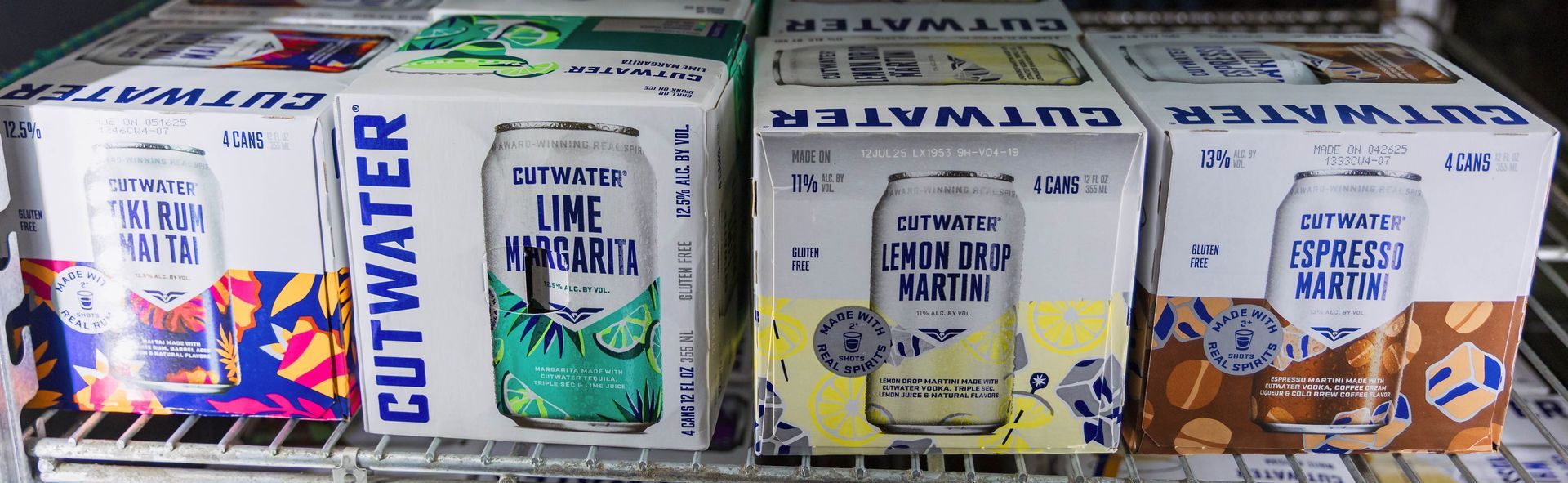 Cutwater canned cocktails in a refrigerator, with different flavors visible: lime, lemon, and more.